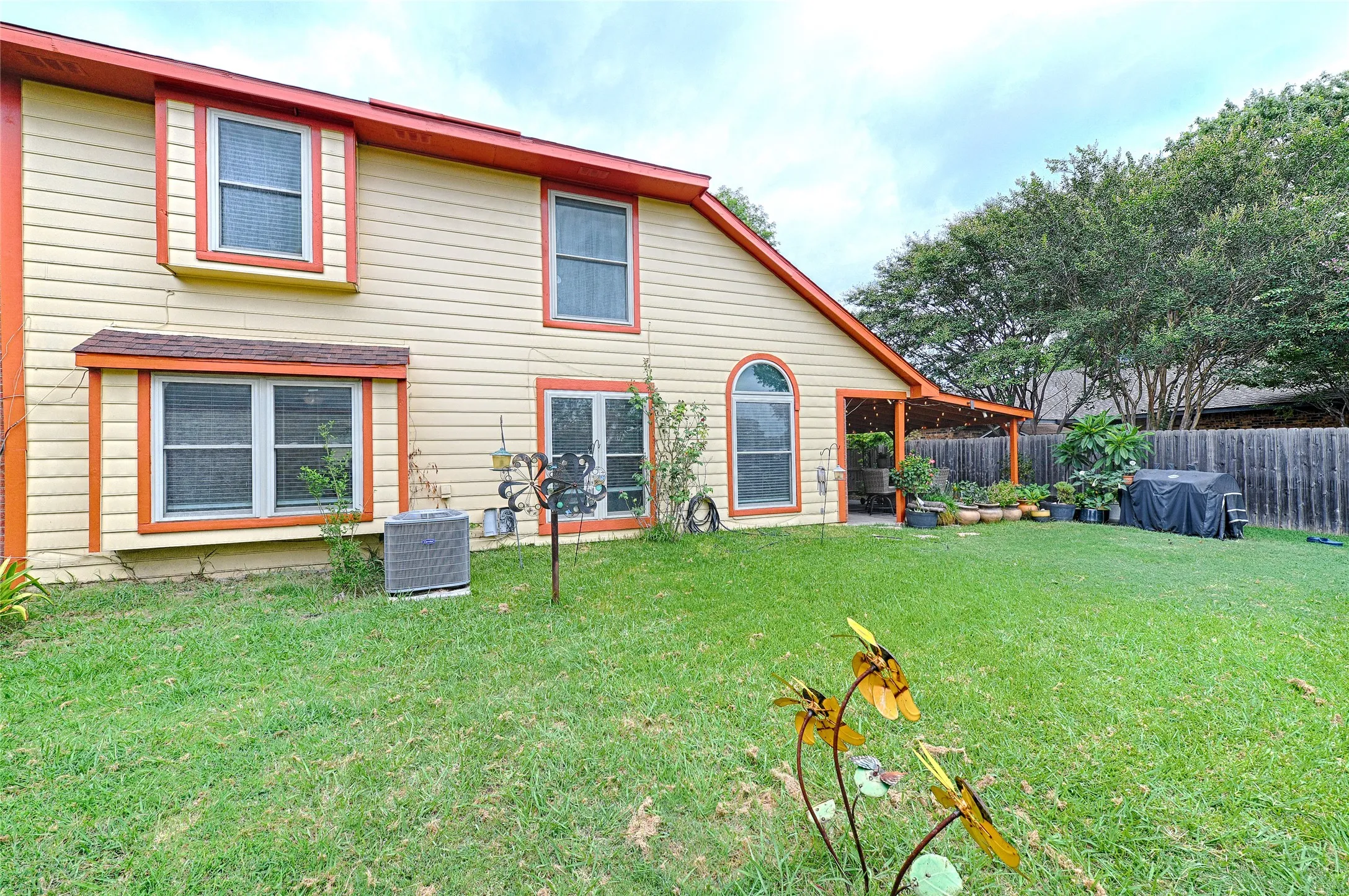 Expansive rear yard featuring a covered patio, board-on-board fencing, and mature trees providing natural screening