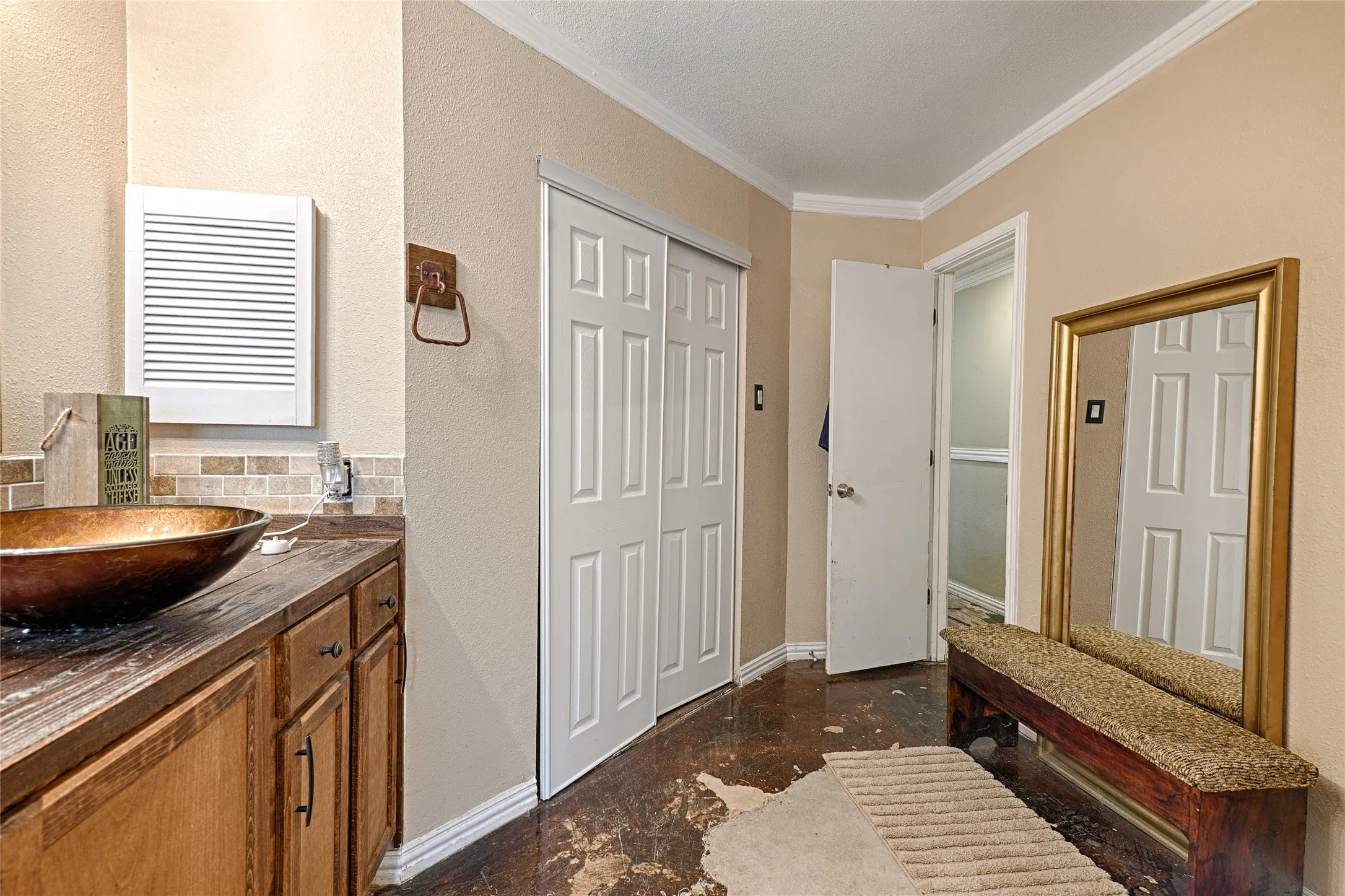 Bathroom vanity with a vessel sink, wood-finish countertop, and tile backsplash