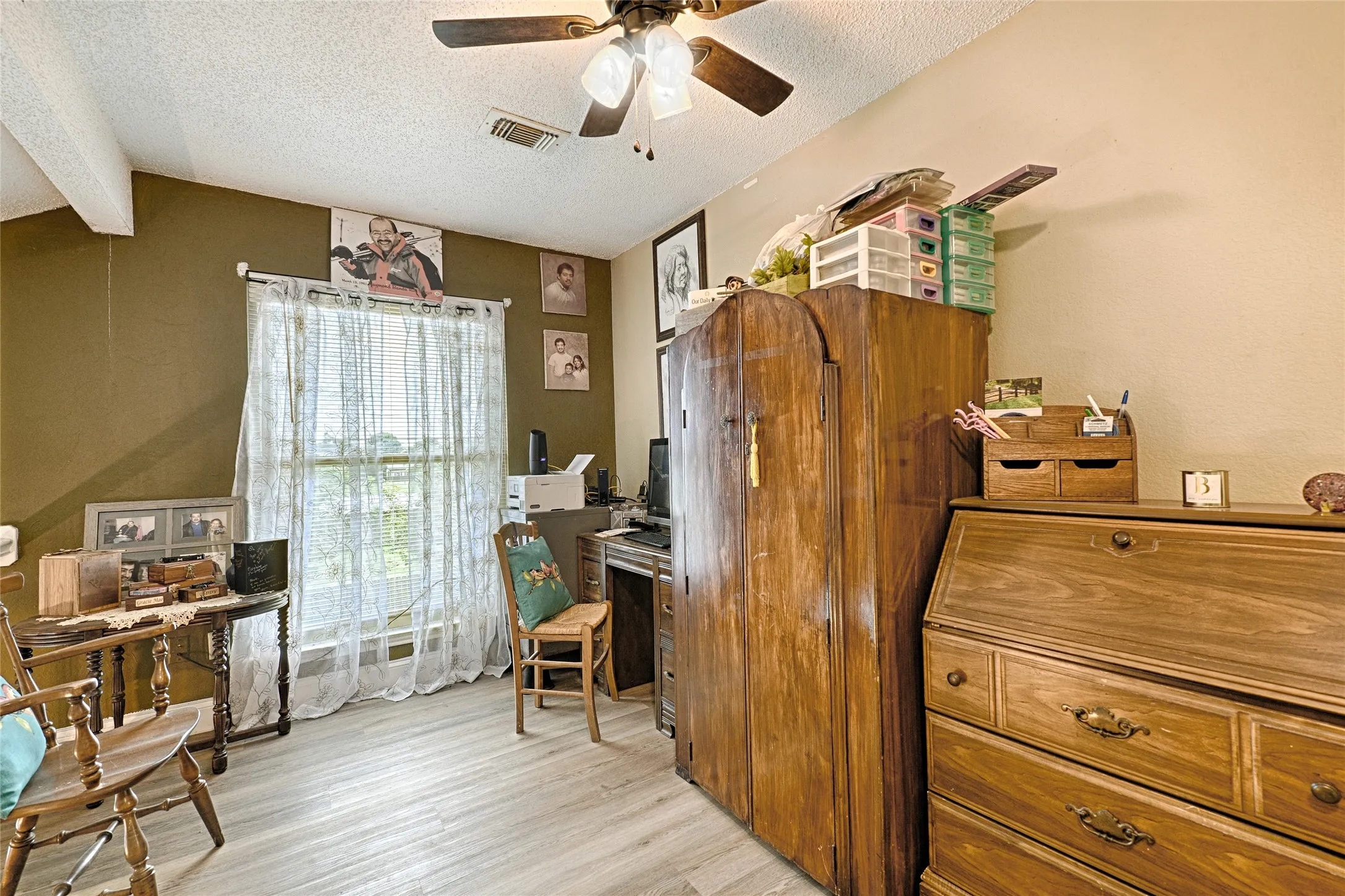 Room featuring light wood-finish flooring, a white textured ceiling, and a ceiling fan with integrated lighting