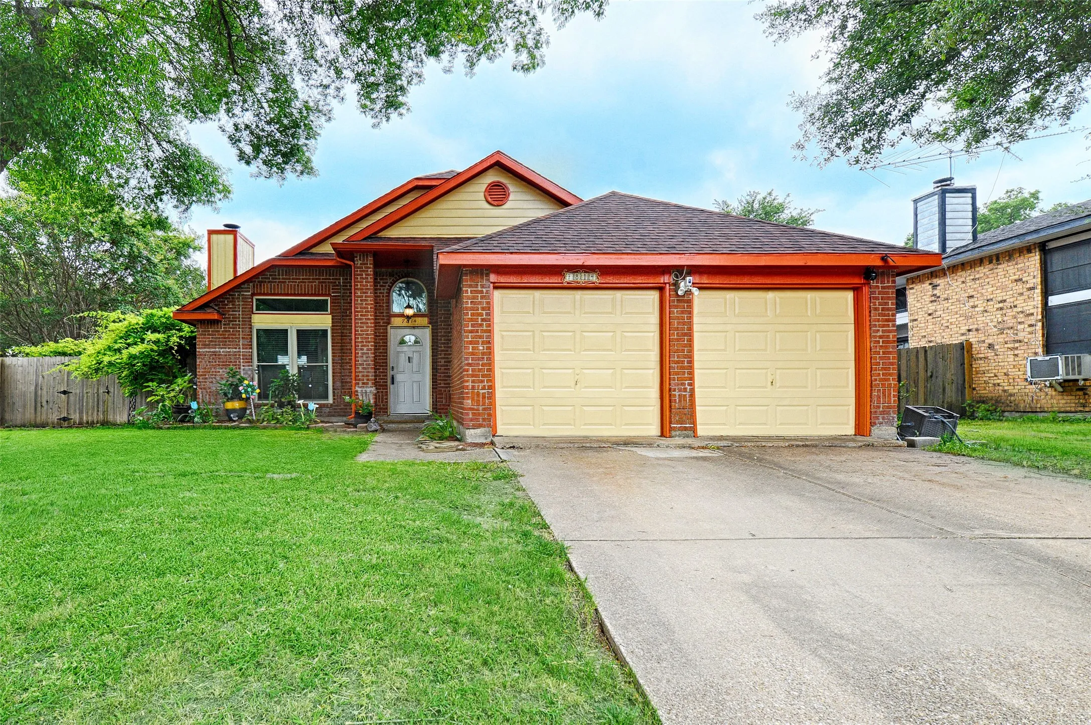 Brick facade residence featuring a two-car garage with panel doors, a concrete driveway, and a front lawn