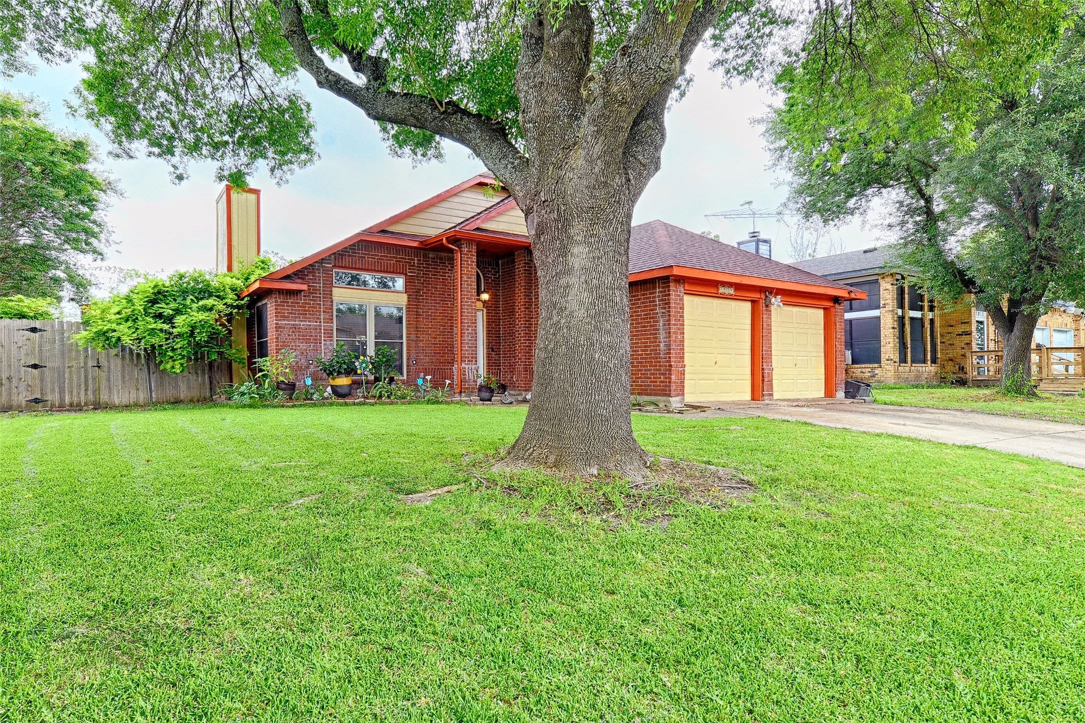 Brick exterior with a prominent mature tree and a well-maintained lawn