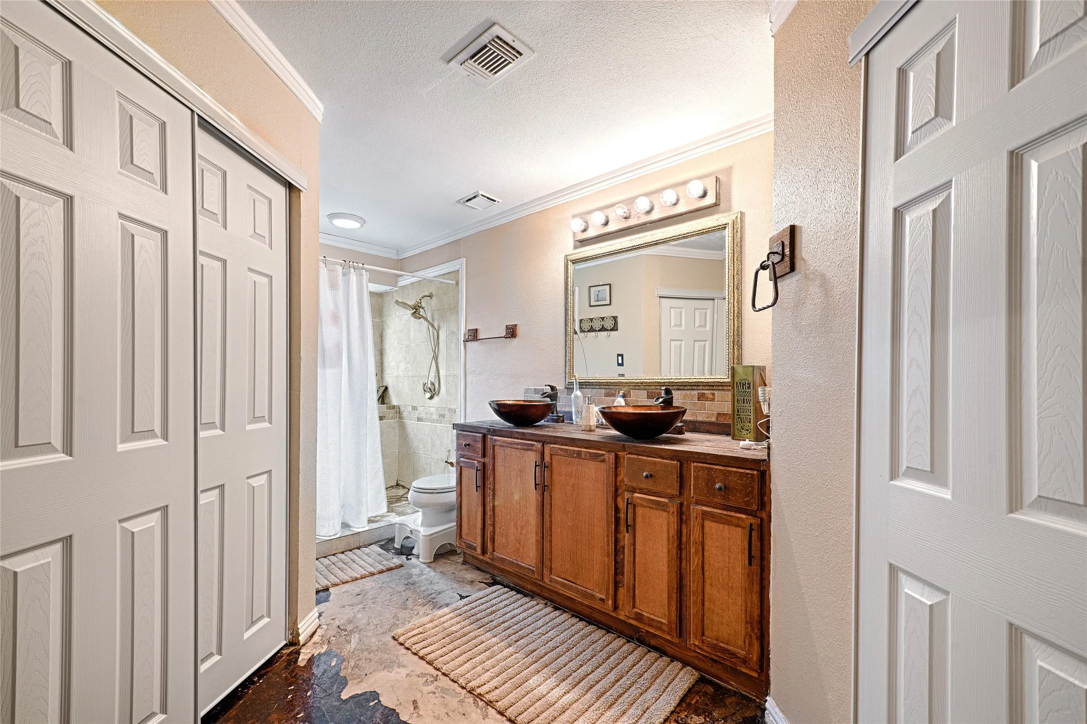 Bathroom featuring a dual vessel sink vanity with wood cabinetry, a tiled shower enclosure with glass panels, and a mirrored medicine cabinet