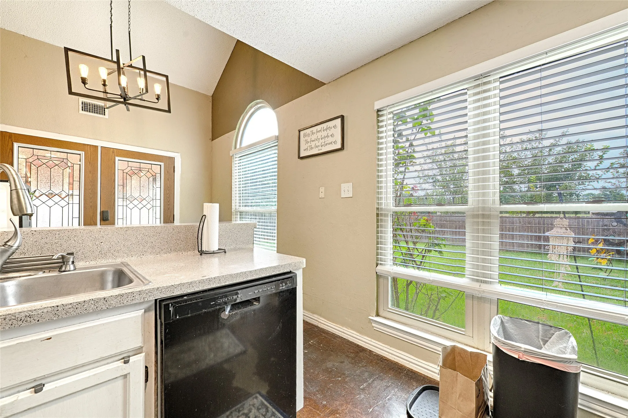 Kitchen area featuring a stainless steel sink, black dishwasher, and speckled countertop