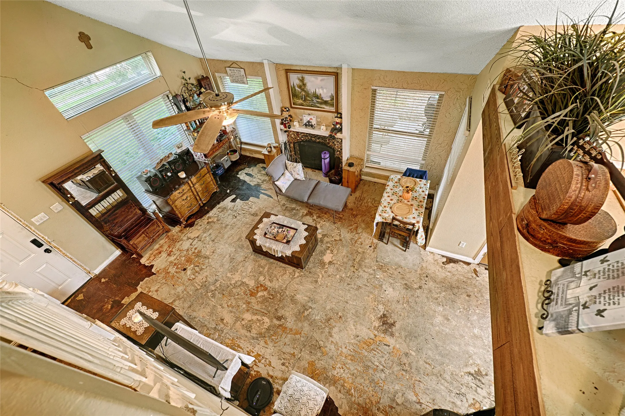 Vaulted ceiling living space featuring a fireplace, a ceiling fan with integrated lighting, and multiple windows with blinds