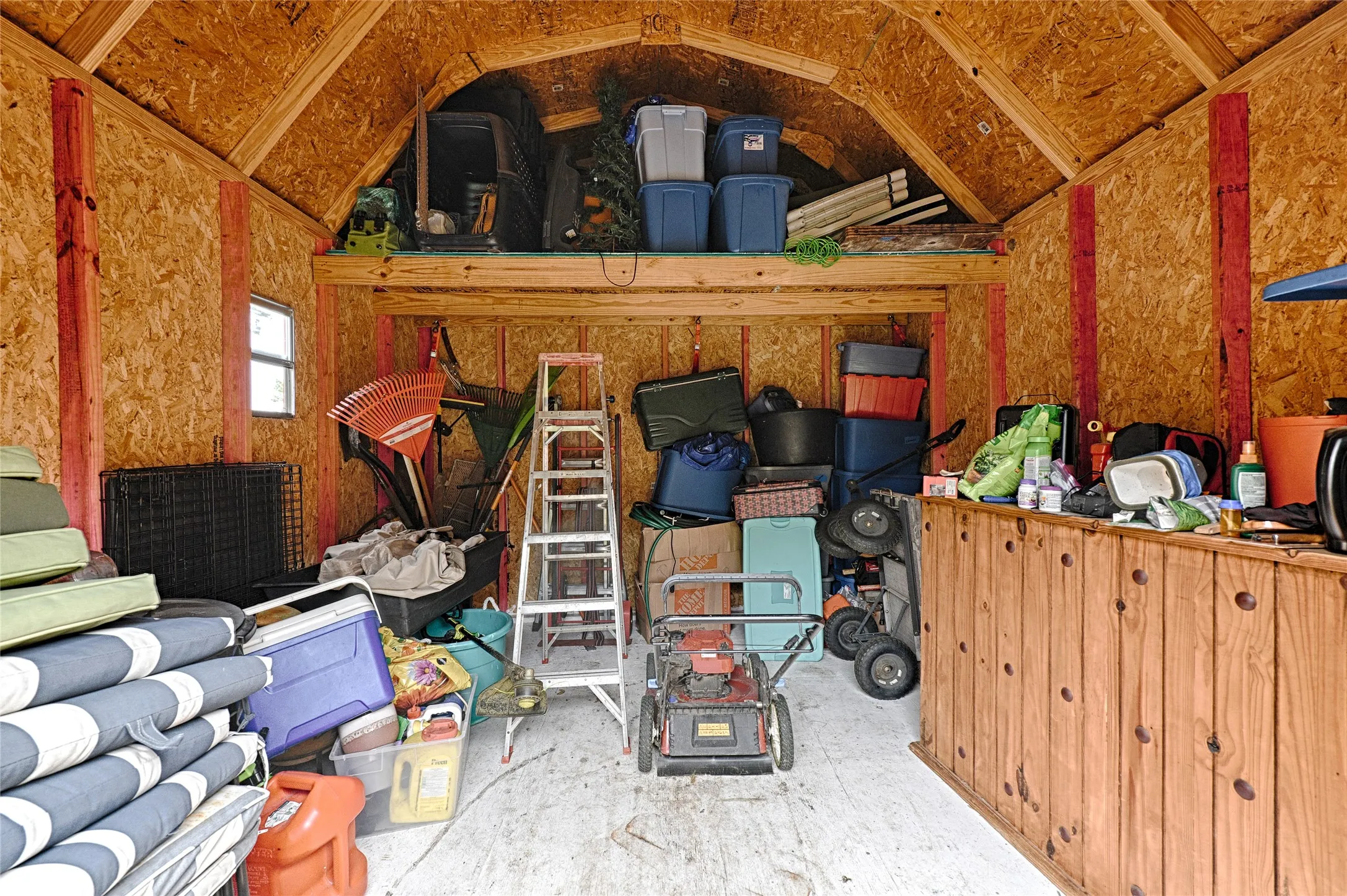 Wood-framed storage shed featuring oriented strand board walls, a gabled roofline, and a built-in wooden workbench