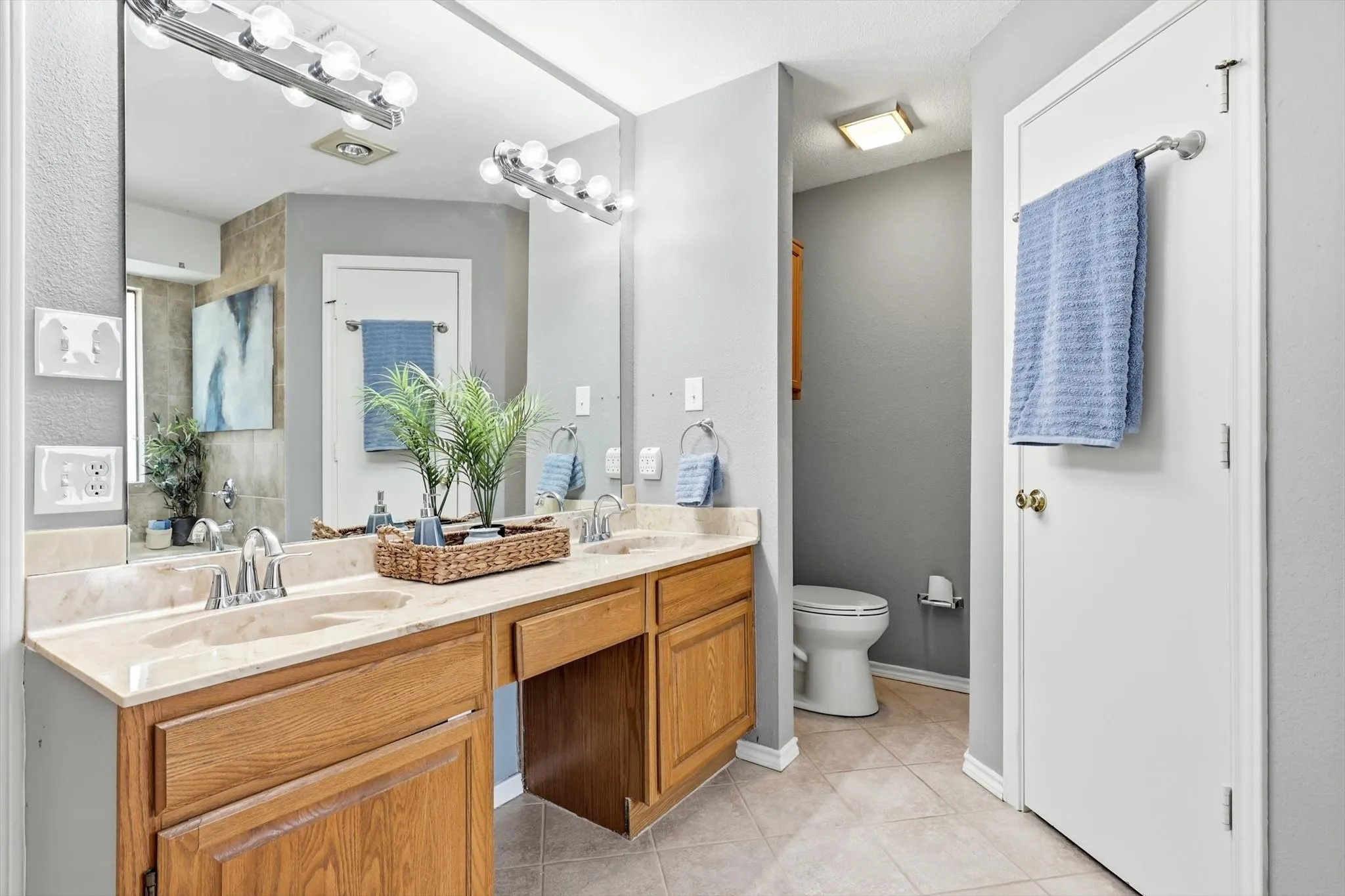 Spa-inspired master bathroom featuring a dual-sink vanity with wood cabinetry, quartz countertop, and chrome fixtures