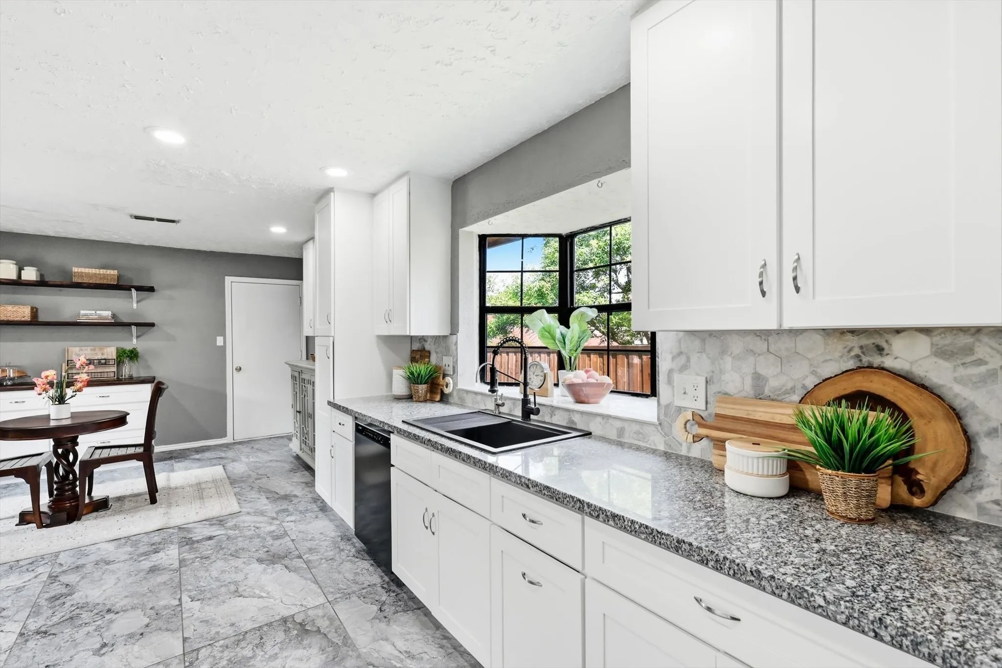 White shaker cabinetry, granite countertops, hexagon tile backsplash, black undermount sink, and recessed lighting