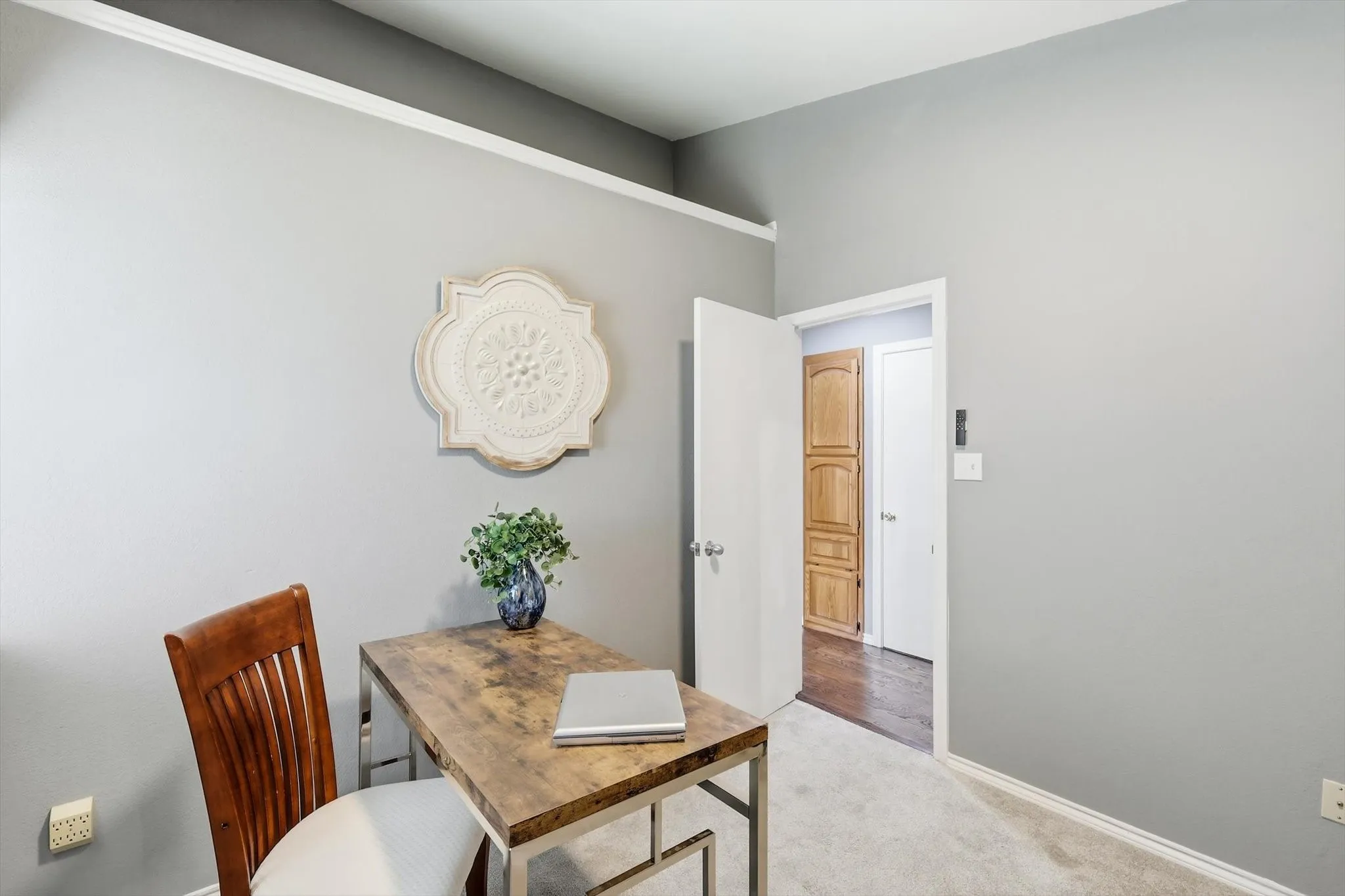 Dedicated workspace or bedroom, featuring a wood-finish desk with metal frame base, wood-slat dining chair, polished concrete flooring, and soft neutral wall palette