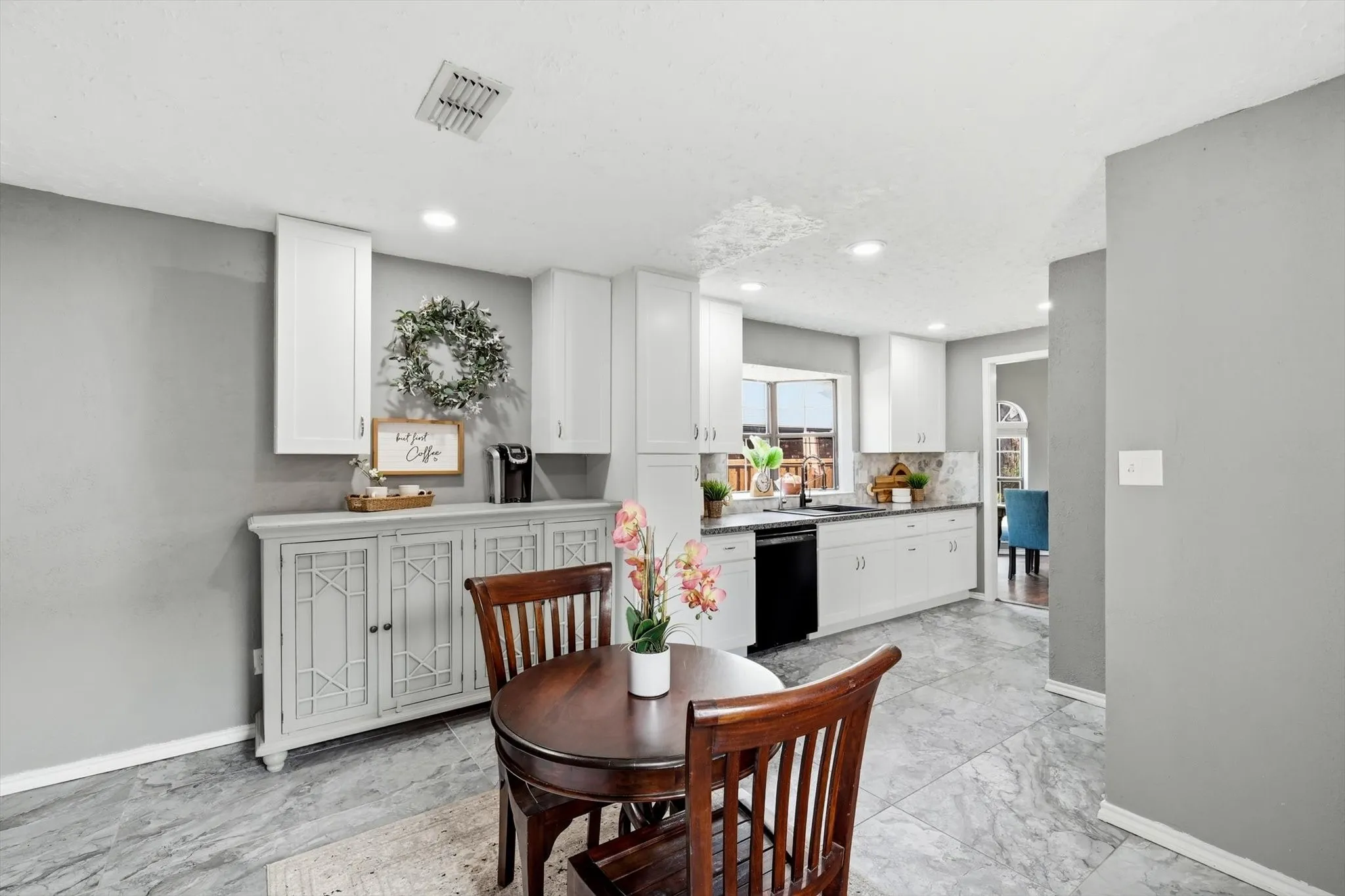 Open-concept kitchen and dining area featuring white shaker-style cabinetry with hardware accents, stainless steel appliances, quartz countertops, and a large island with seating