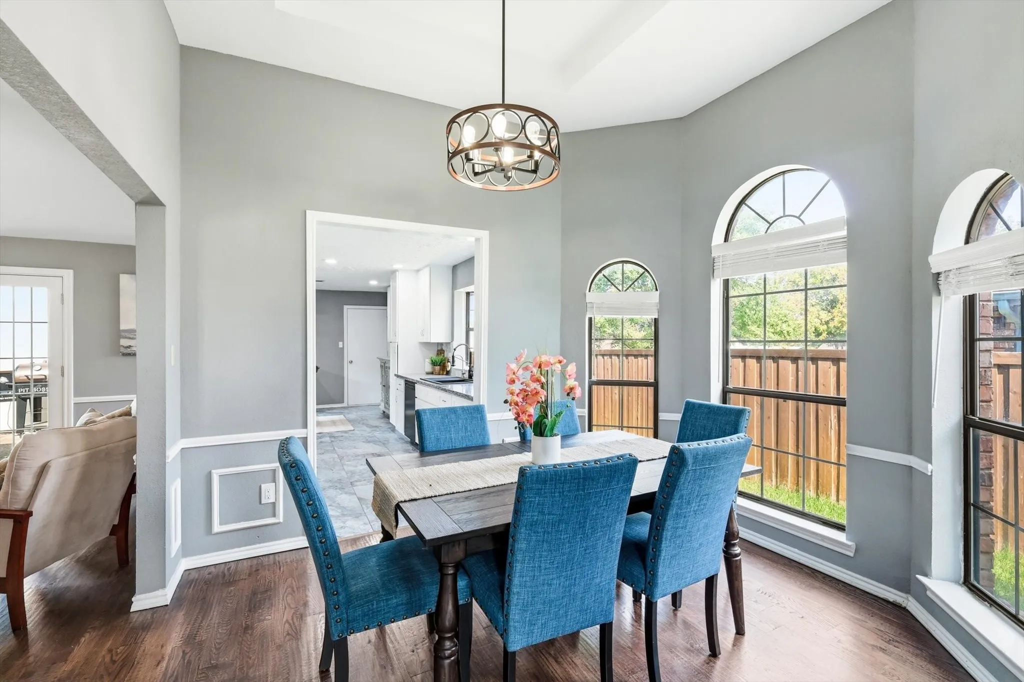 Elegant dining room featuring a wood-finish table, upholstered blue chairs, and a pendant light fixture