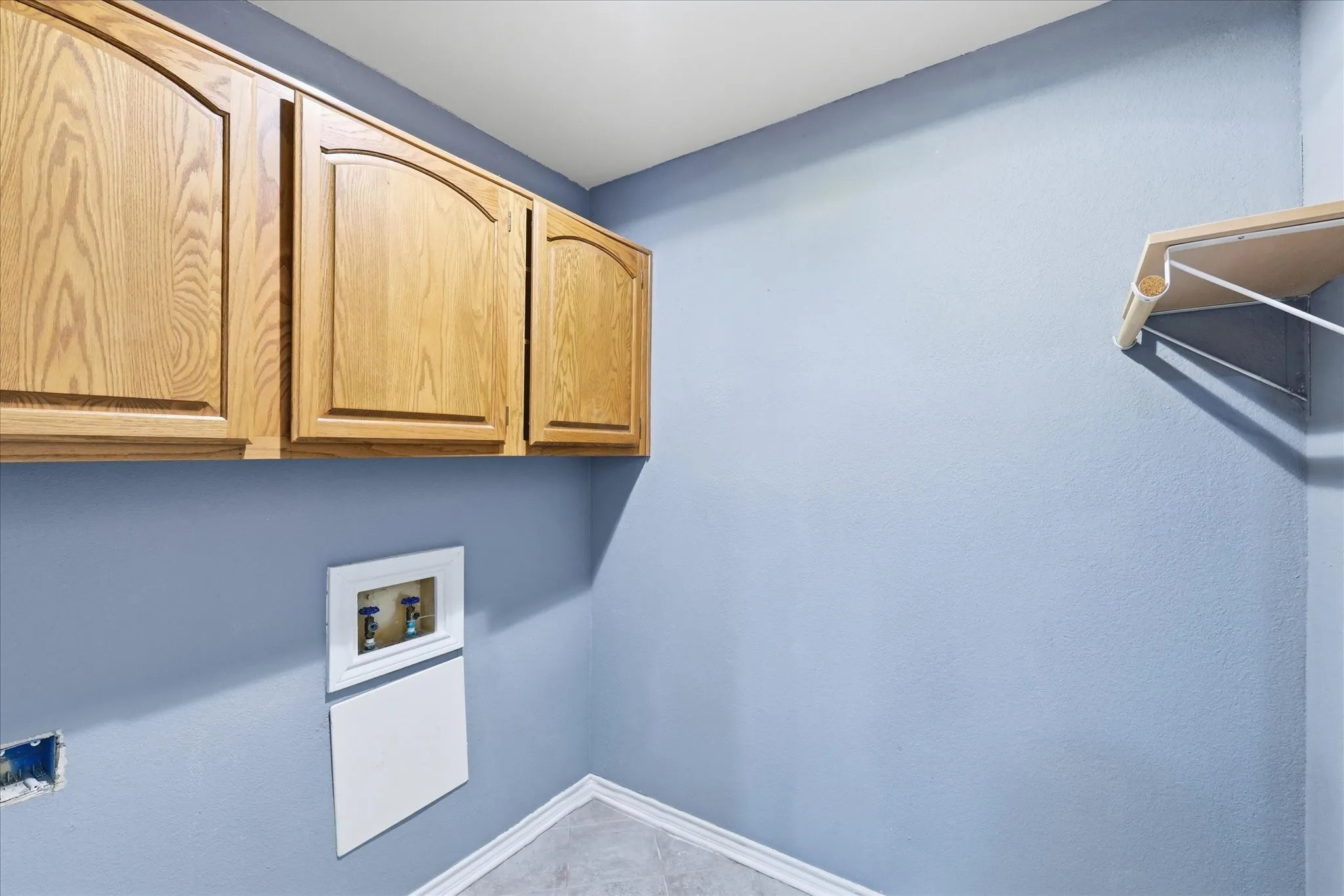 Built-in cabinetry with arched panels, wall-mounted shelving, and tile flooring