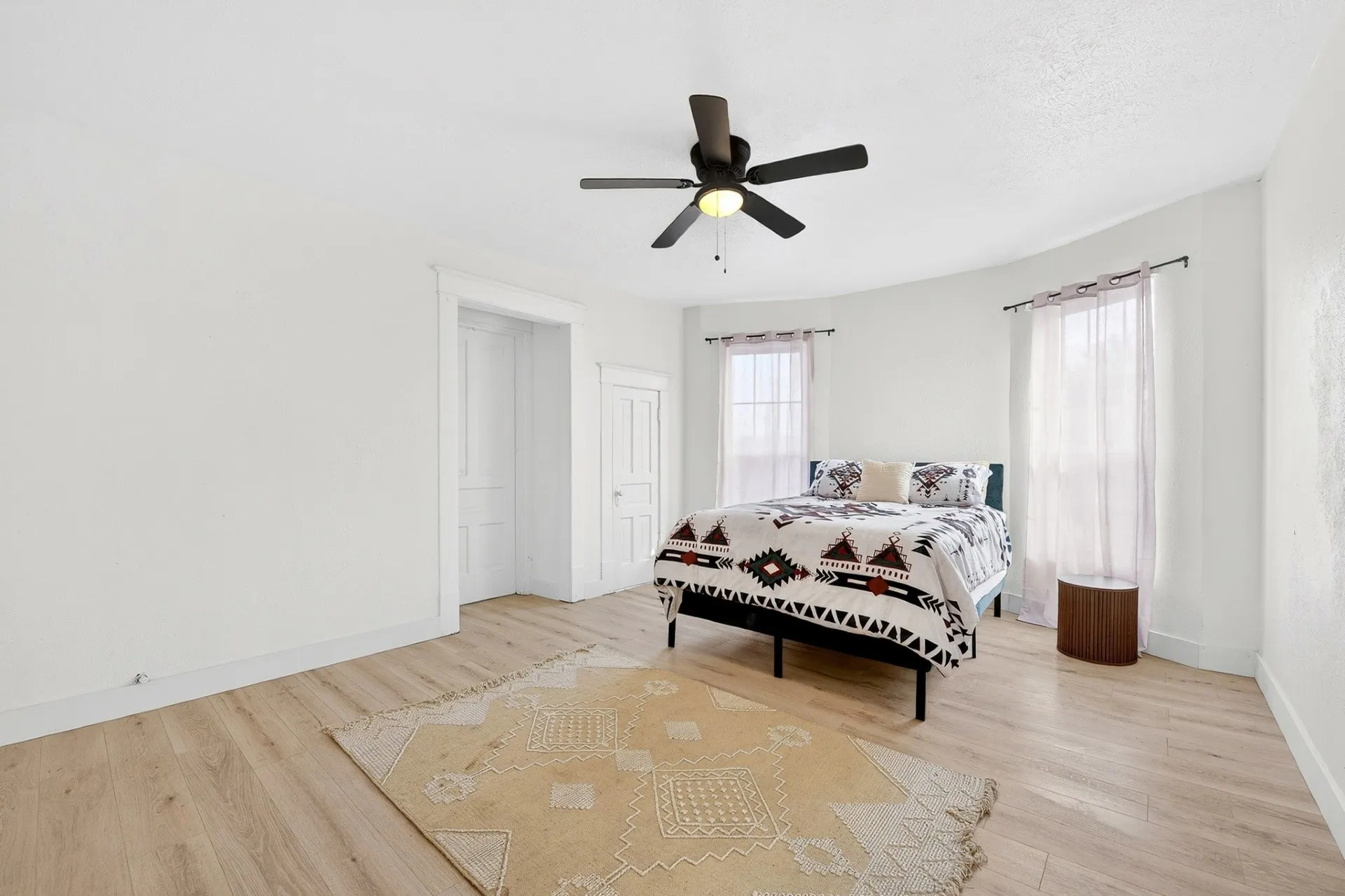 Light wood-finish flooring complements white walls in this bedroom