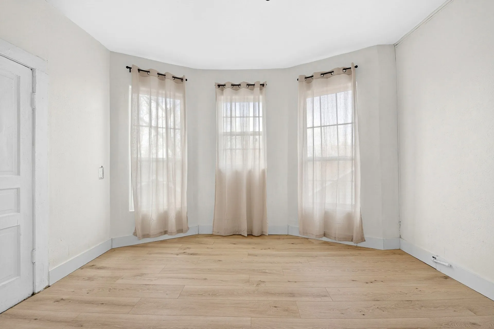 Hardwood-style flooring and a bay window configuration featuring three individual windows