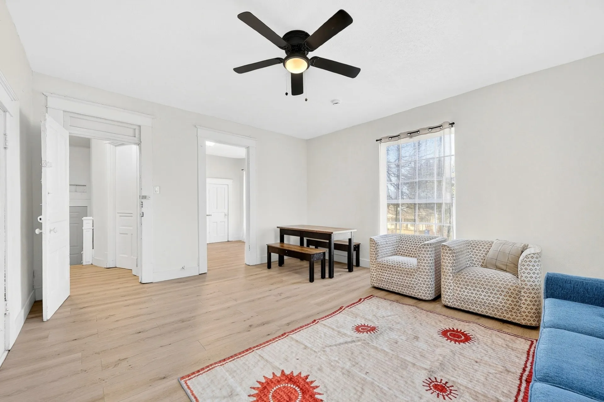 Spacious interior featuring light wood-finish flooring, a ceiling fan with integrated lighting, and multiple open doorways