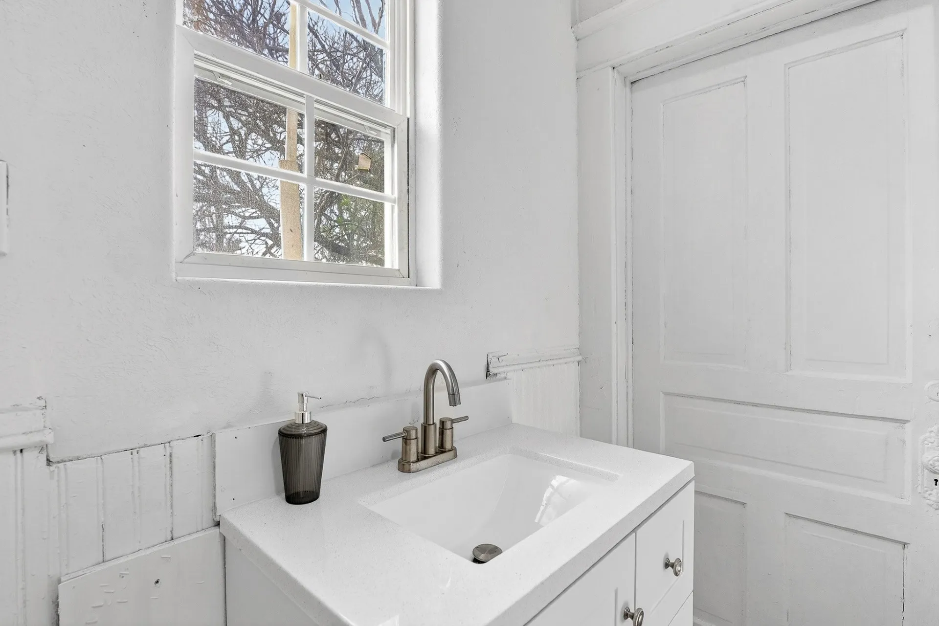White vanity with integrated sink, two-handle faucet, and cabinet storage
