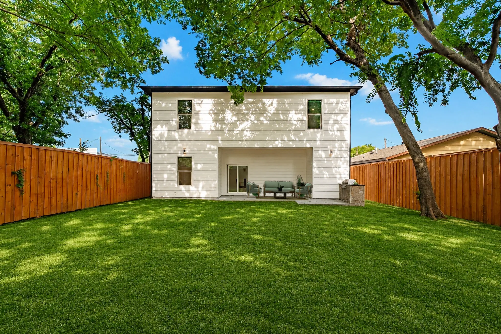 Backyard Facing Back Of The House Showcasing The Covered Porch With Built-In Grill.  This Has Been Virtually Staged And Grass Has Been Virtually Greened.