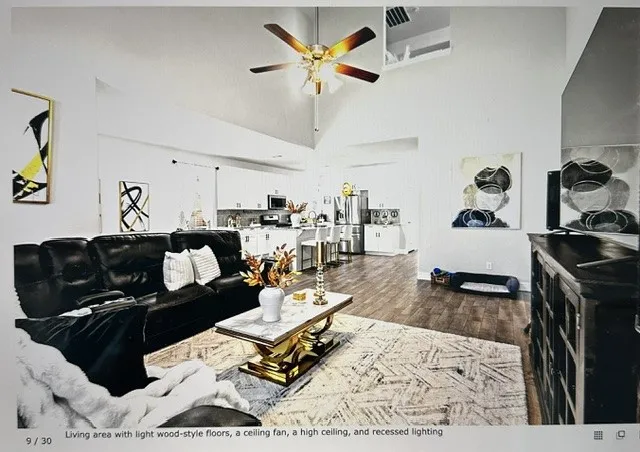 Spacious living area featuring high ceilings, wood-style flooring, a ceiling fan, and recessed lighting