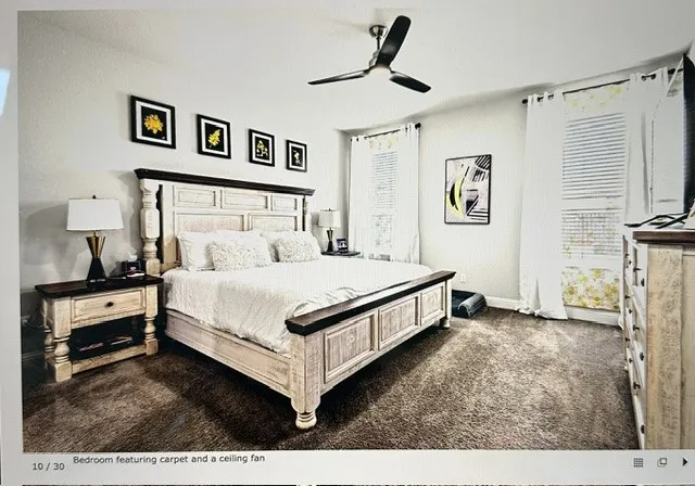 Carpeted room featuring a ceiling fan, window blinds, and white curtains