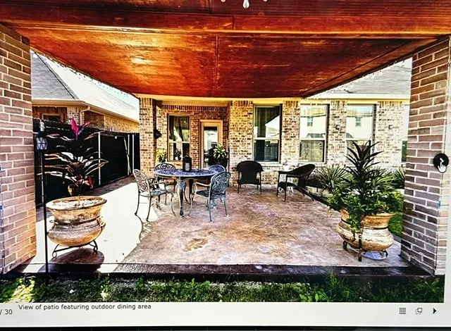 Covered patio featuring a stained wood ceiling, brick columns, and a stamped concrete surface