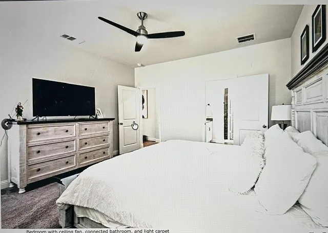 Bedroom with ceiling fan, connected bathroom, and light carpet
