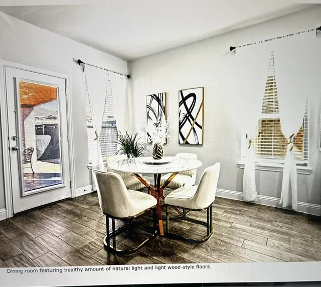 Dining area featuring wood-finish flooring, two large windows with blinds, and a glass-paneled door