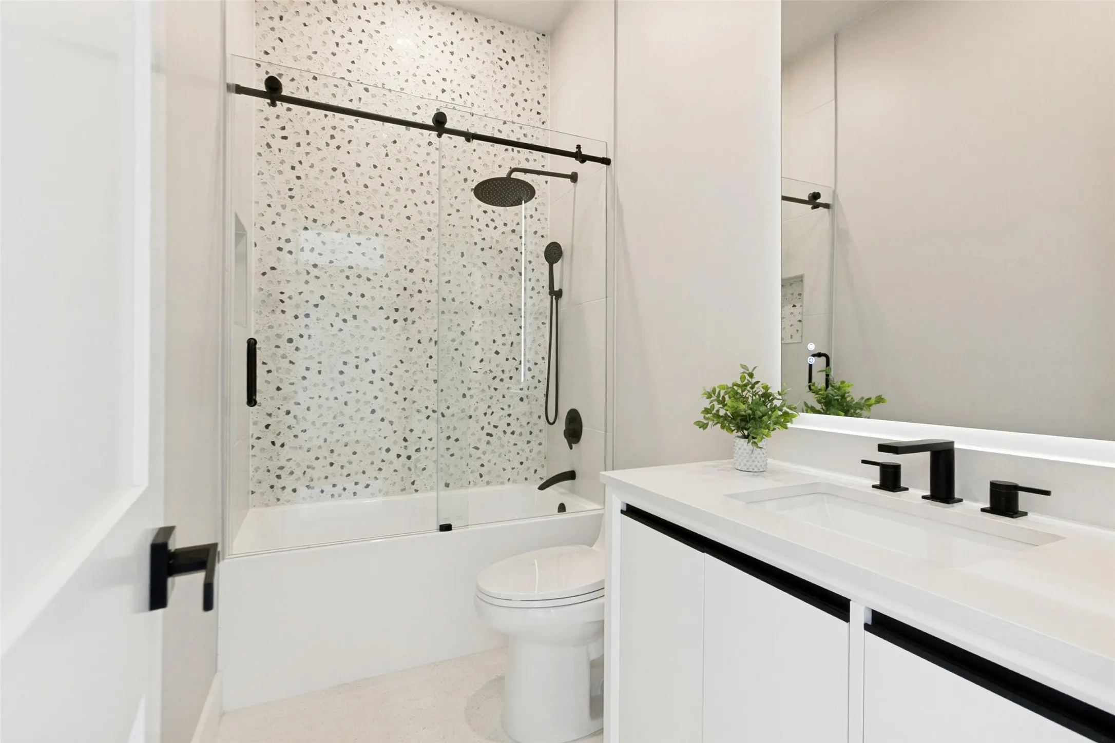 Bathroom to #4 bedroom with white vanity with quartz top, matte black fixtures, designer tile and a large mirror.