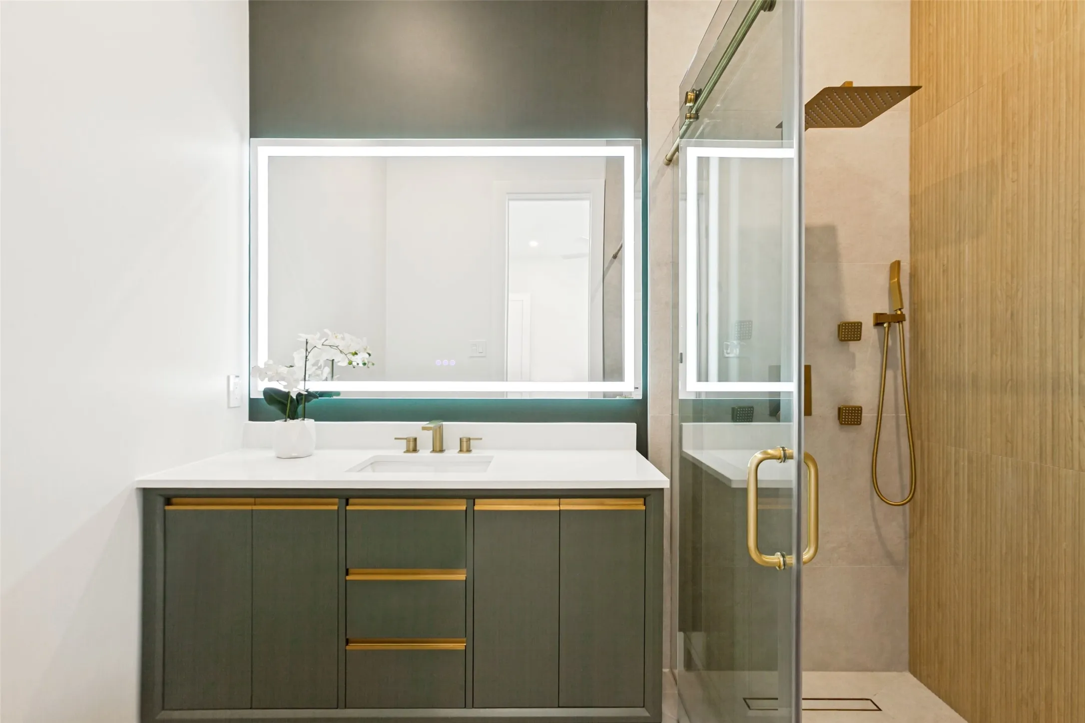 Guest bedroom bathroom with modern vanity with quartz countertop, back lit anti fog mirror and brushed gold hardware and plumbing fixtures.