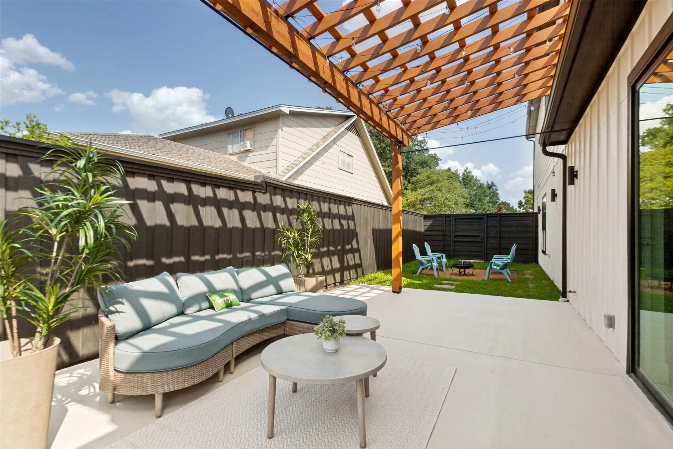 Relaxing outdoor living area featuring a wood pergola, expansive concrete patio, and fenced yard
