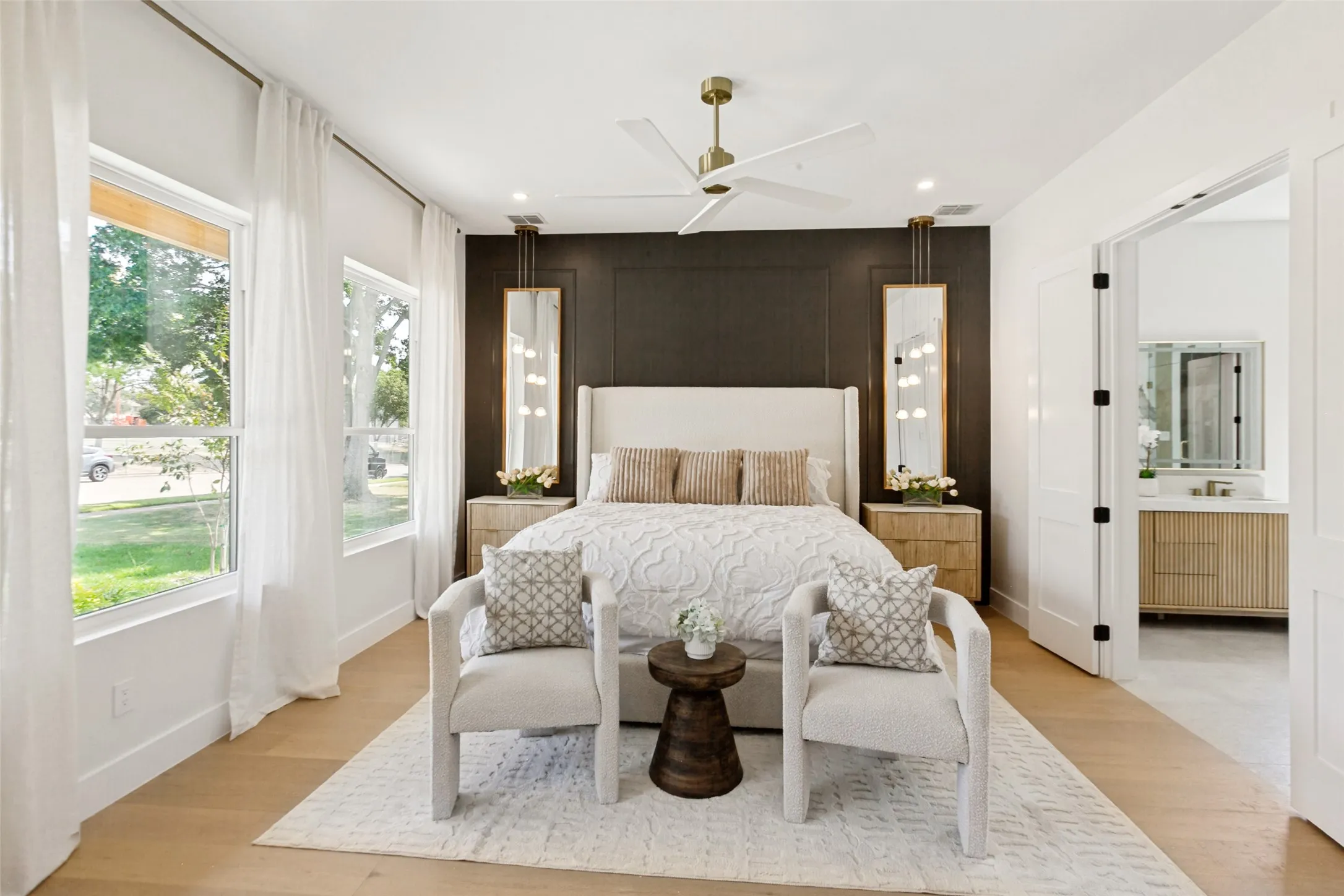 Primary bedroom with oak wood flooring, designer light fixtures, recessed lighting, and a modern ceiling fan.