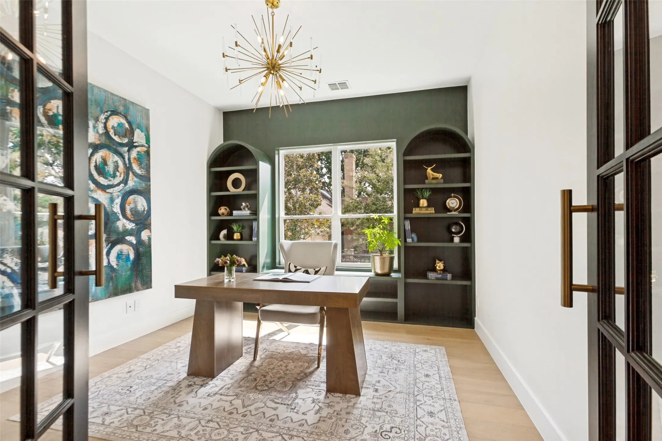 Office featuring white oak wood flooring, designer sputnik chandelier, and custom built-in arched bookcases.