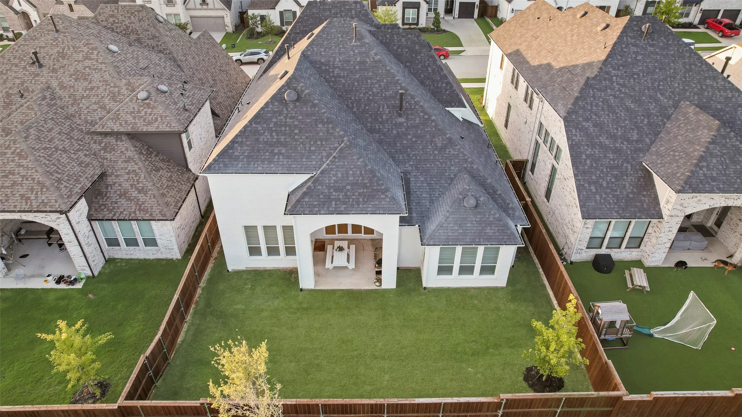 Expansive backyard featuring a manicured lawn, a covered patio with an outdoor dining set, and a stained wood privacy fence