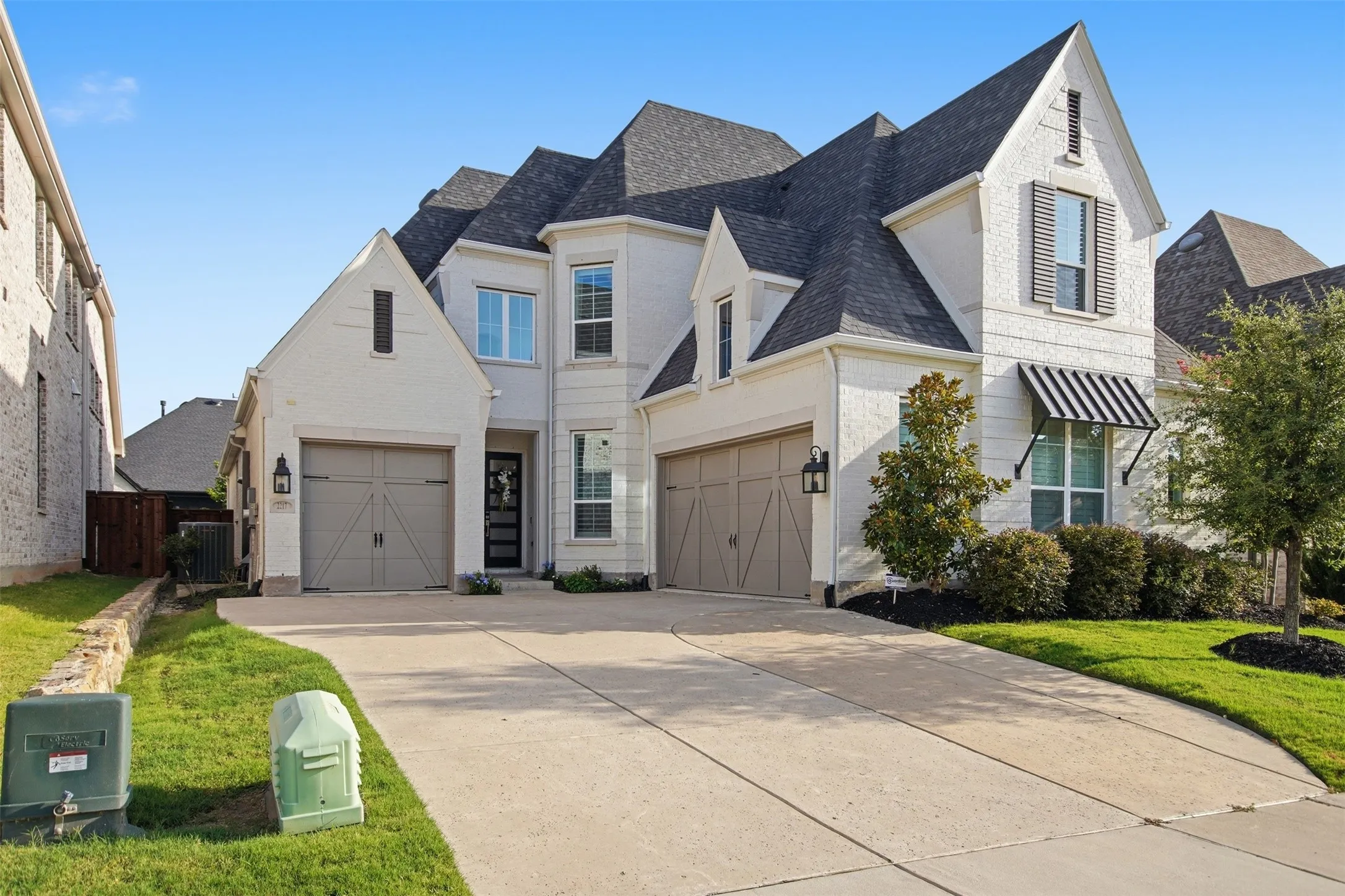White brick exterior featuring a multi-gabled roofline and dark gray shingles