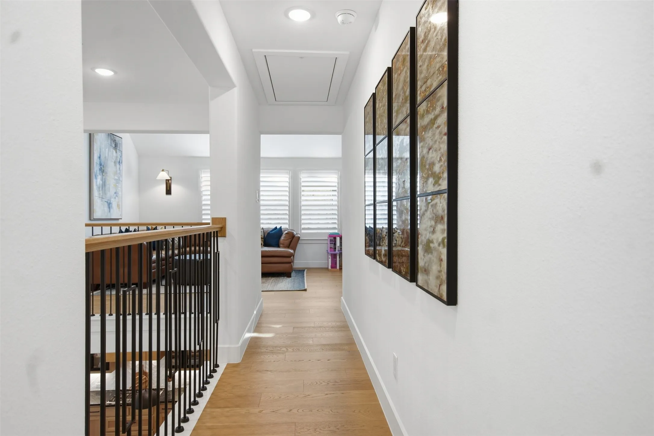 Hallway featuring wood-finish flooring, recessed lighting, and a white balustrade with black spindles