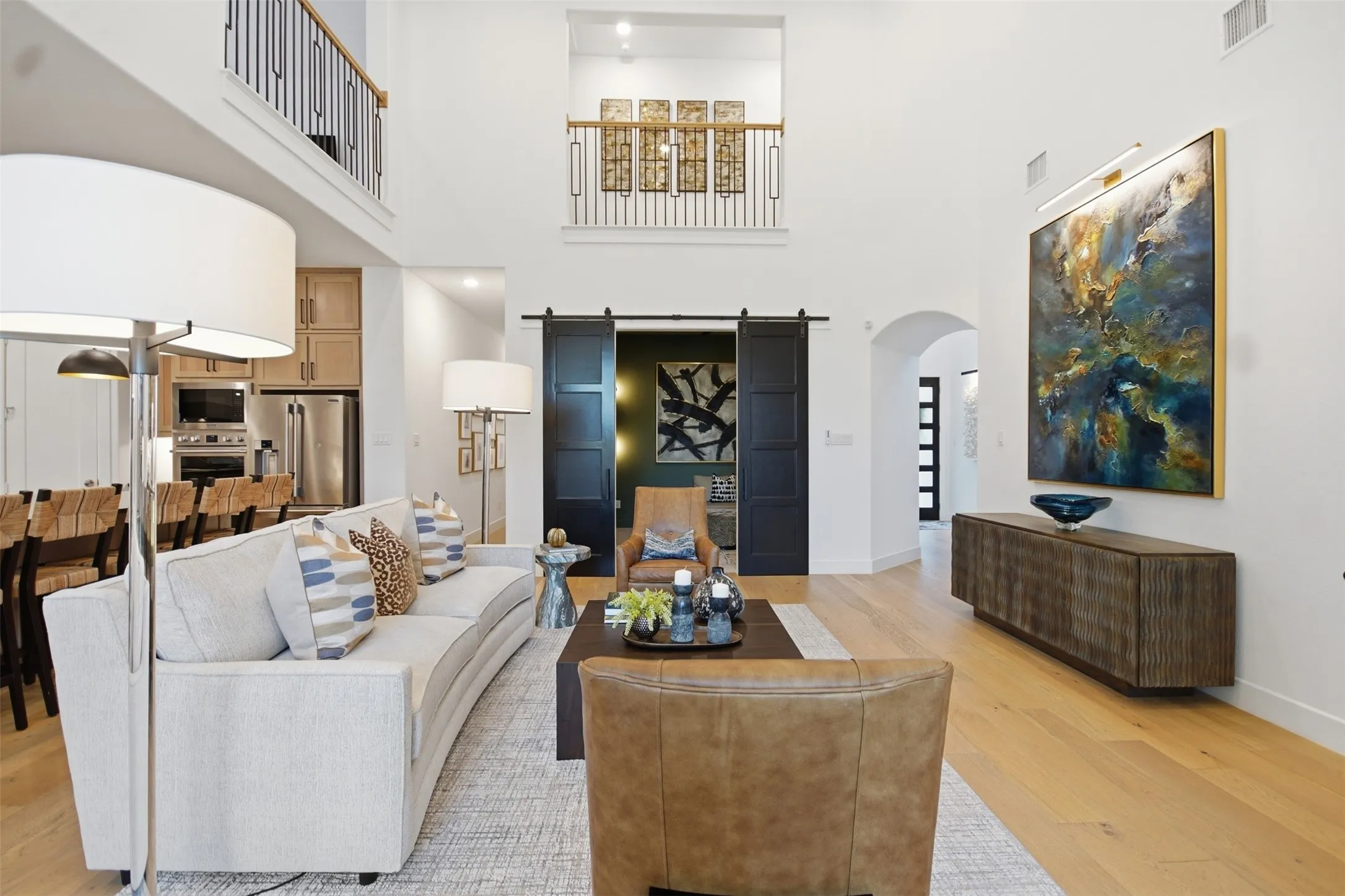 Open-concept living space featuring high ceilings and wood-finish flooring, 1st floor media room with custom barn doors, open balconies, custom kitchen cabinets & tasteful designer selections throughout!