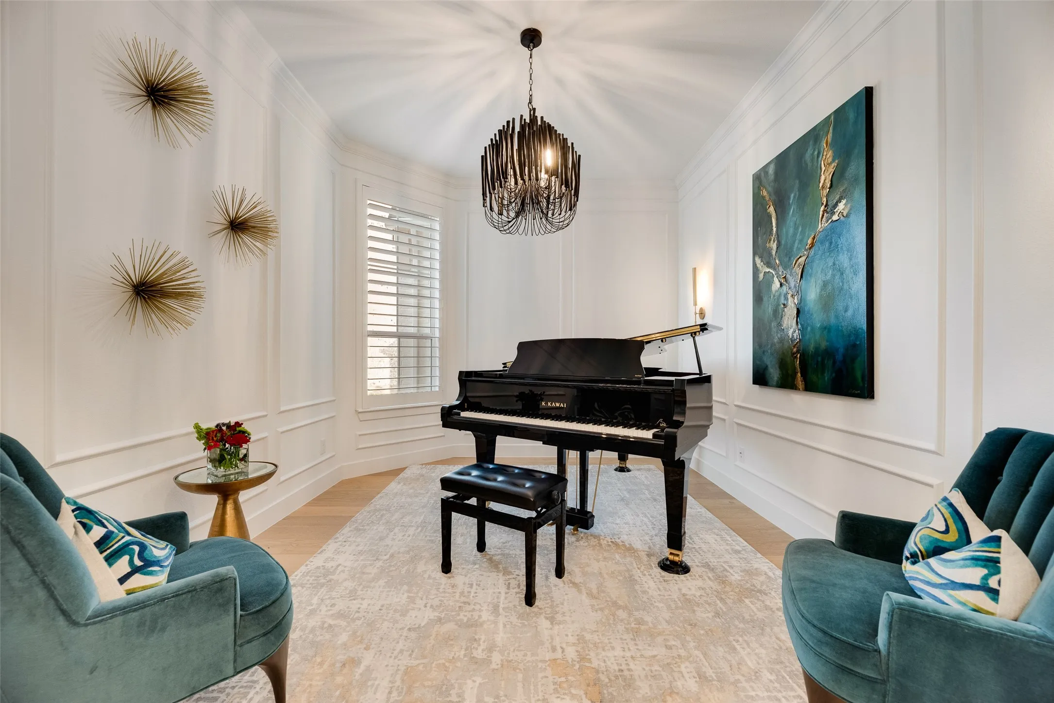 Room featuring light wood-finish flooring, white walls with decorative molding, and a central chandelier