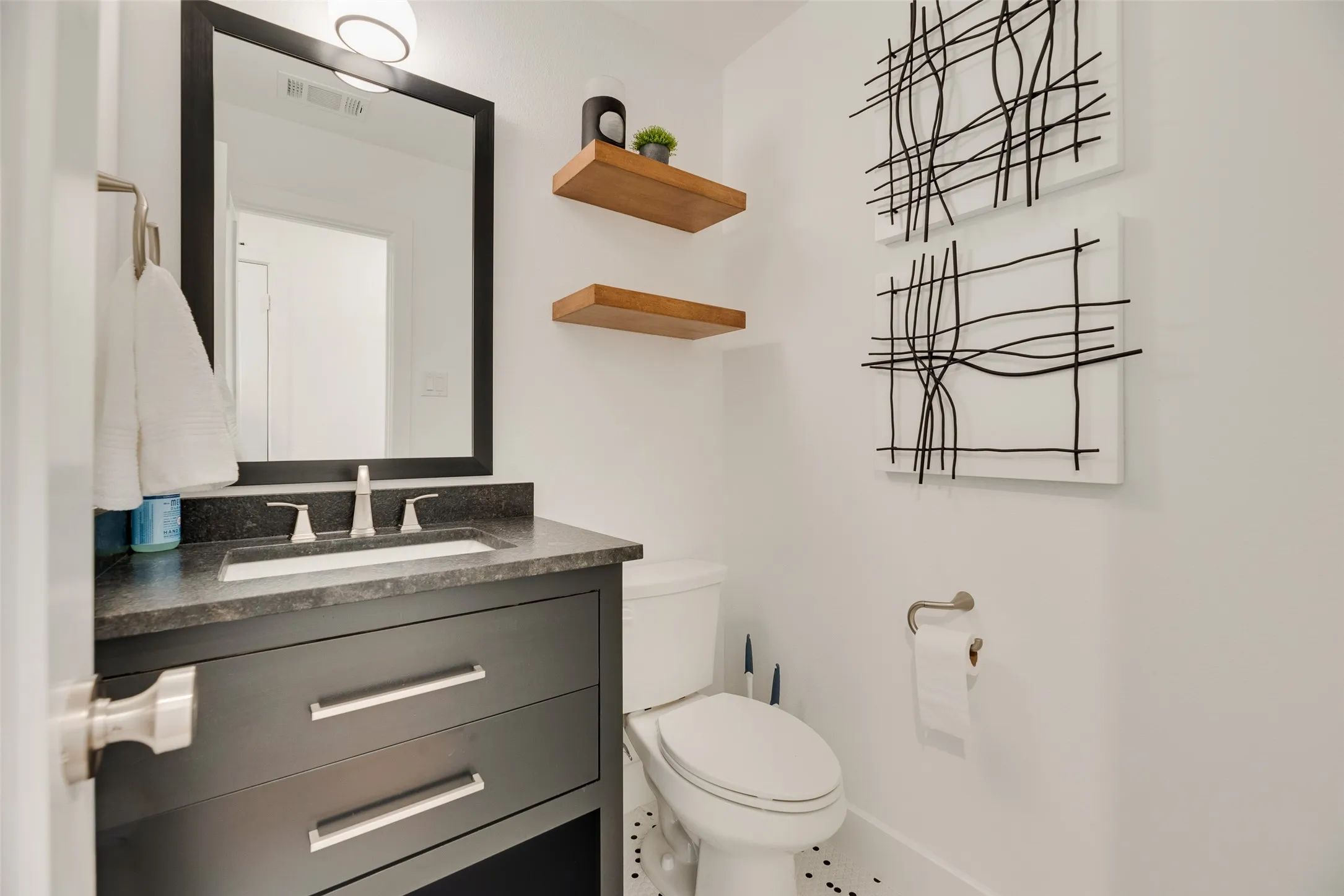 Upstairs Powder Room -  featuring a dark vanity with a white rectangular sink, dark countertop, and brushed nickel hardware