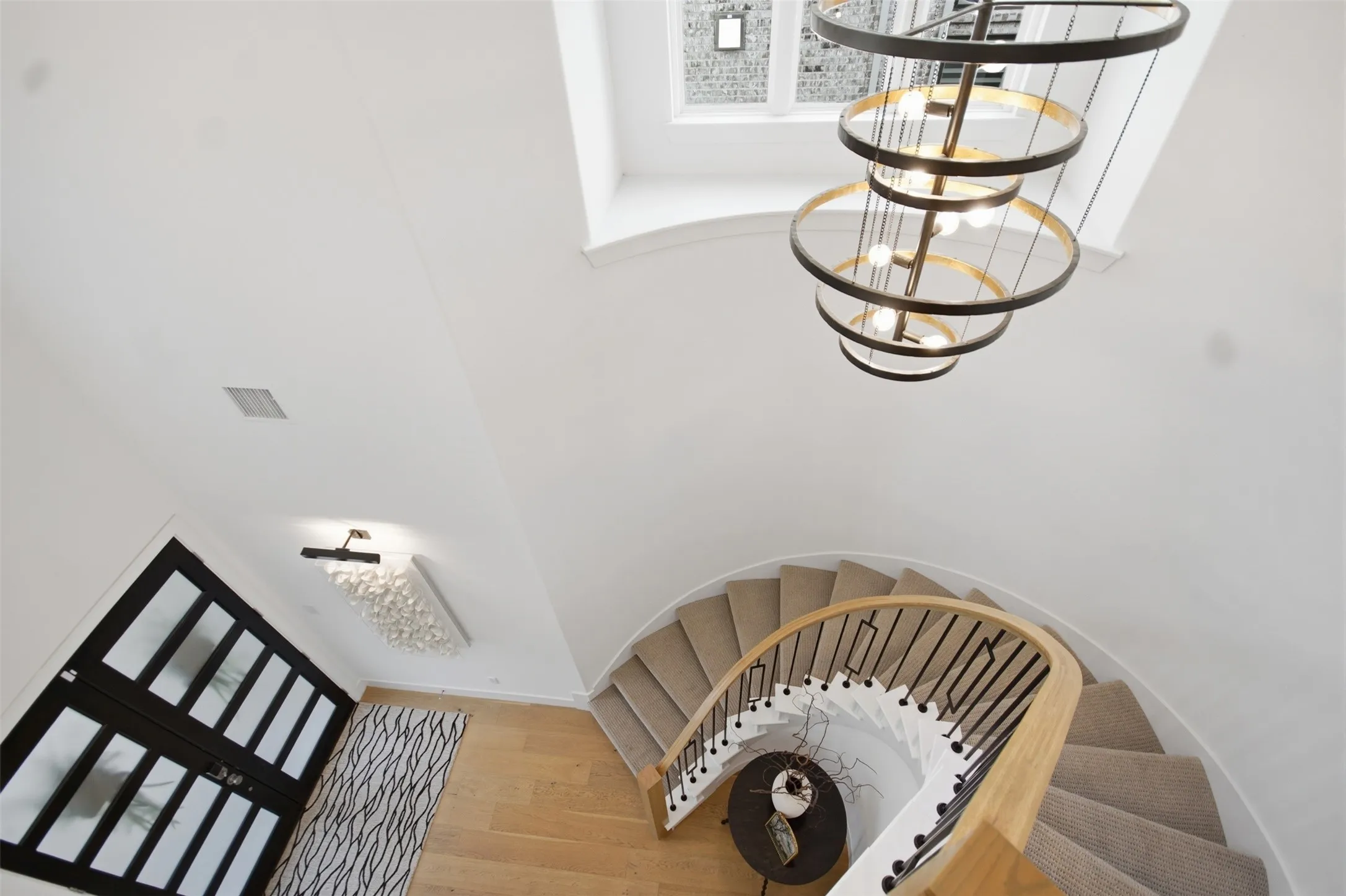 Foyer featuring a grand spiral staircase with carpeted treads, a light wood handrail, and wrought iron balusters