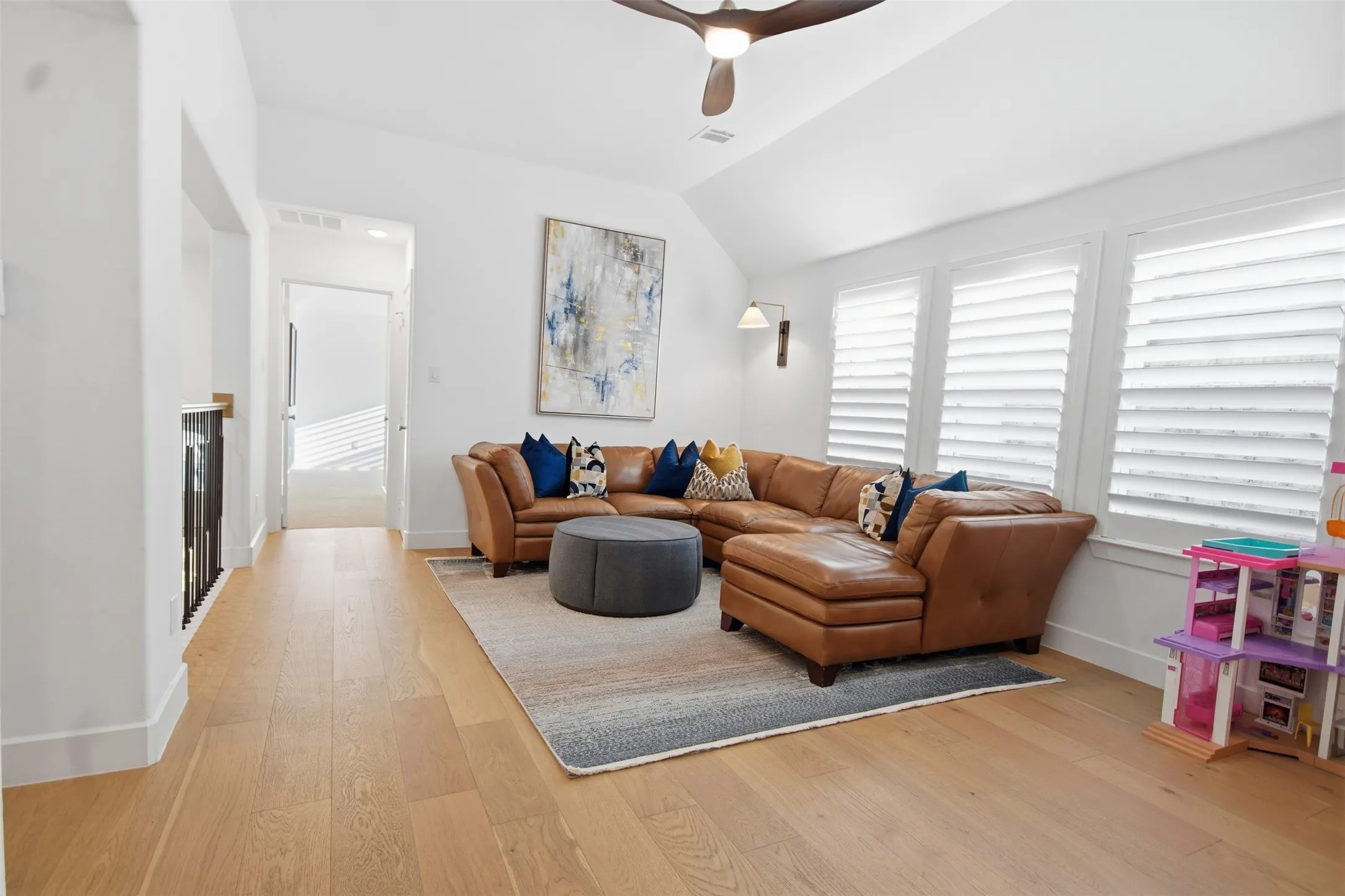 Spacious bonus room featuring wood-finish flooring, vaulted ceiling, and multiple windows with plantation shutters