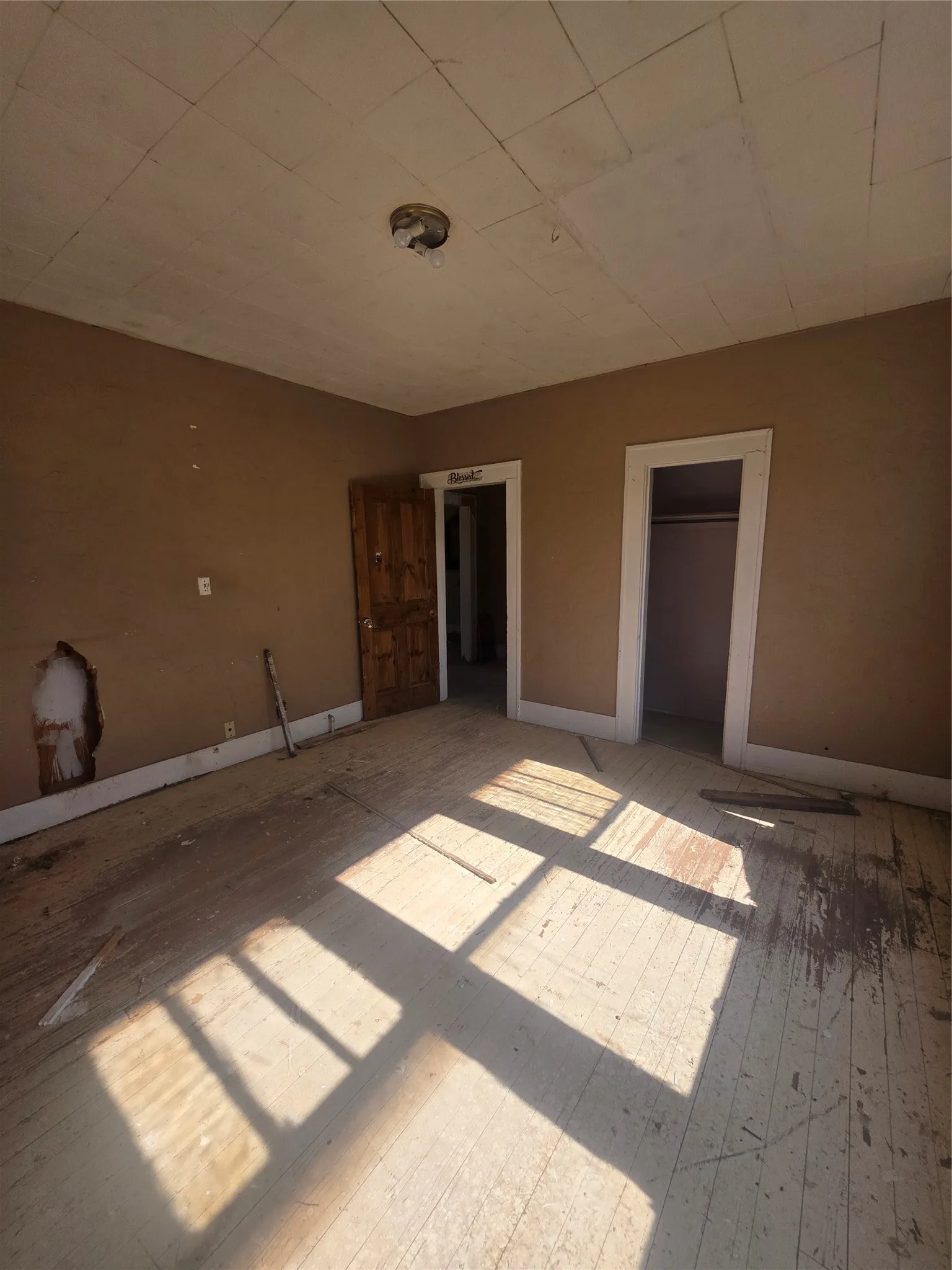 Room featuring wood-finish flooring, a light fixture, and two doorways with trim