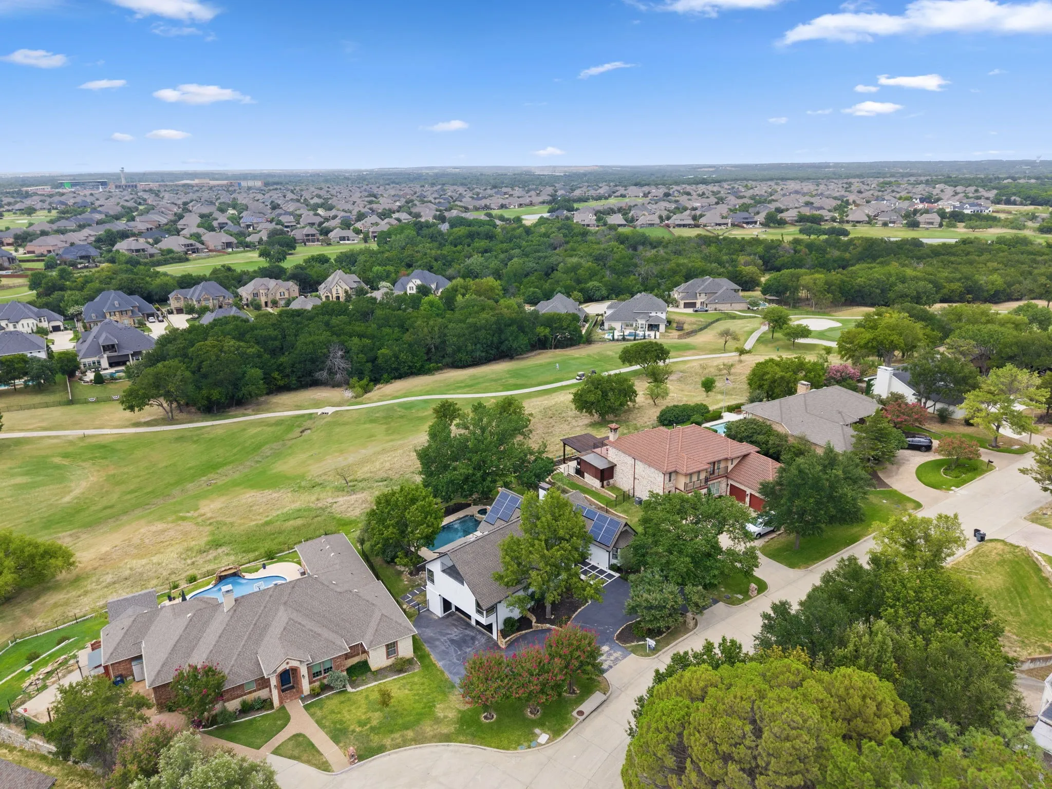 Aerial perspective showcasing a residential community with abundant green spaces and mature trees