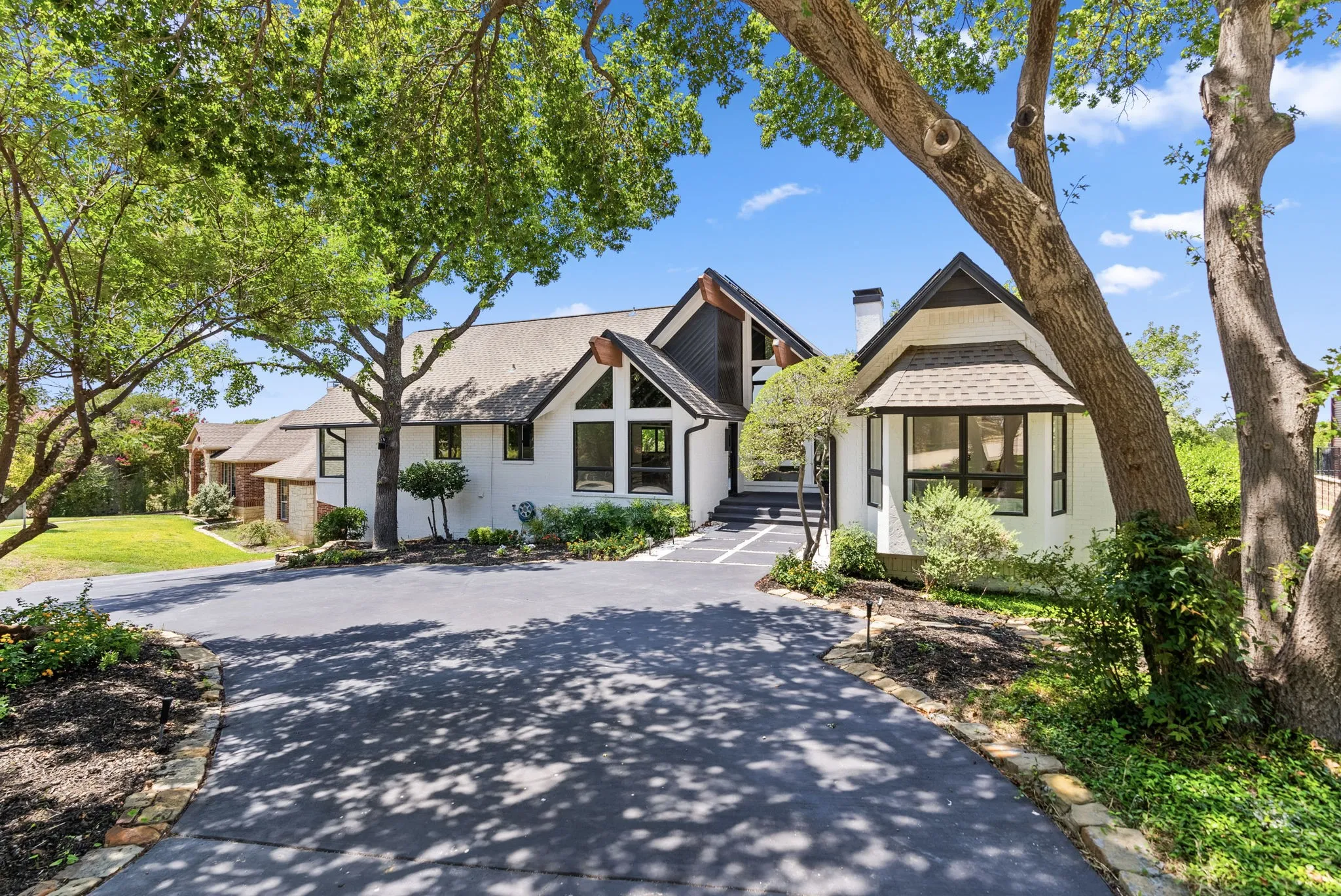 Contemporary white exterior with dark trim accents, a multi-pitch roofline, and a prominent bay window