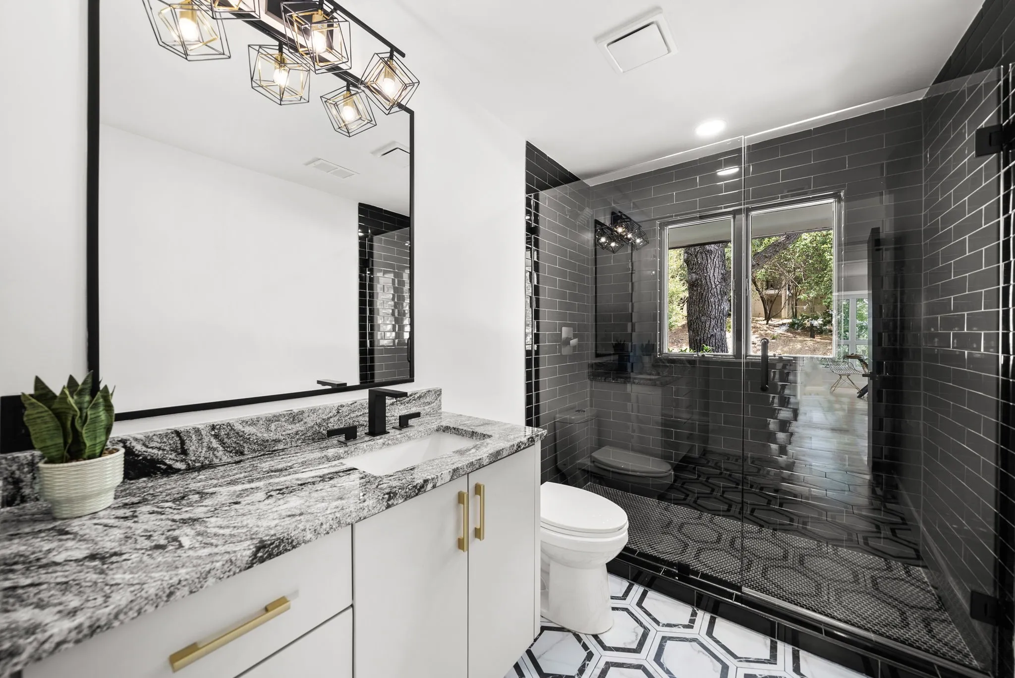 Custom vanity featuring a patterned stone countertop, integrated sink, and matte black hardware