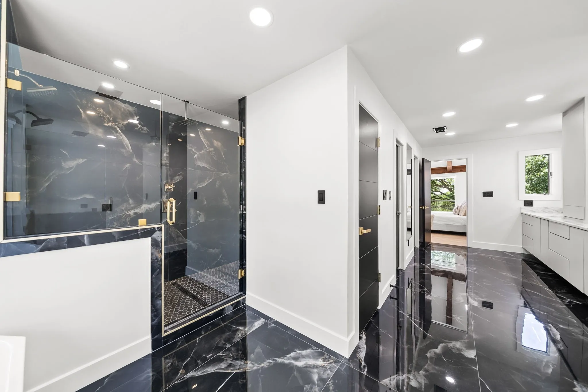 Spacious bathroom featuring black marble-style flooring, a large glass-enclosed shower with black marble-style walls, recessed lighting, and a white vanity with a light-colored countertop