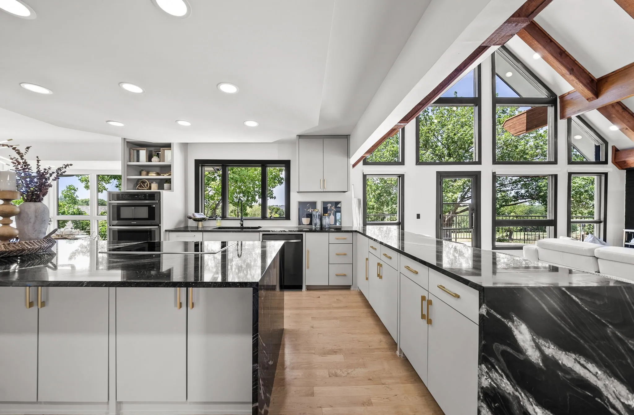 Modern kitchen featuring dual islands with dark stone countertops, light-toned cabinetry, and recessed lighting