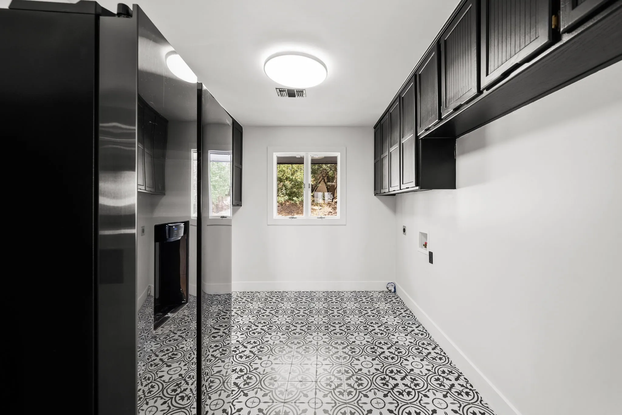 Utility room featuring black upper cabinetry, a single window, and a patterned floor