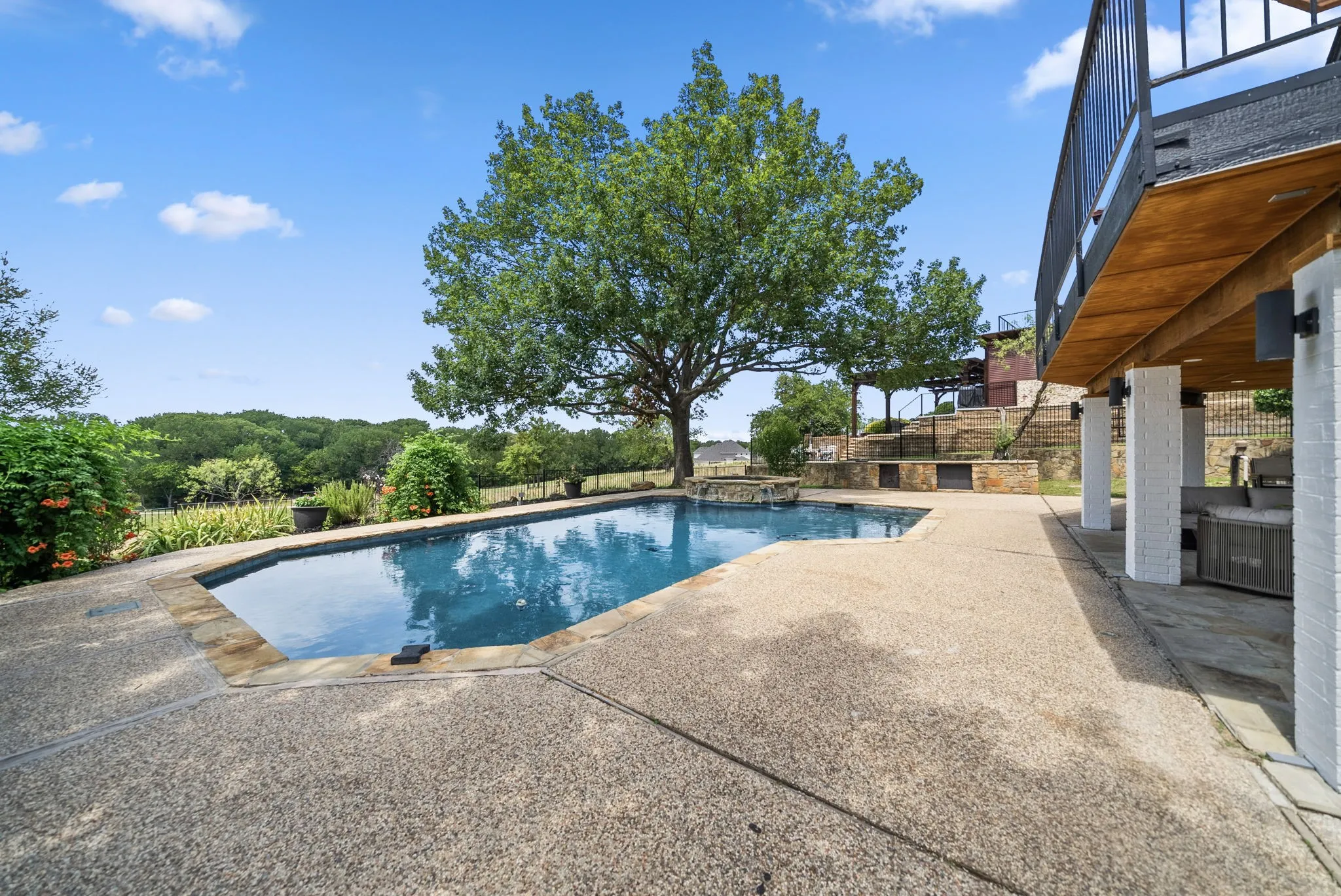 In-ground swimming pool with flagstone coping and surrounding aggregate concrete decking