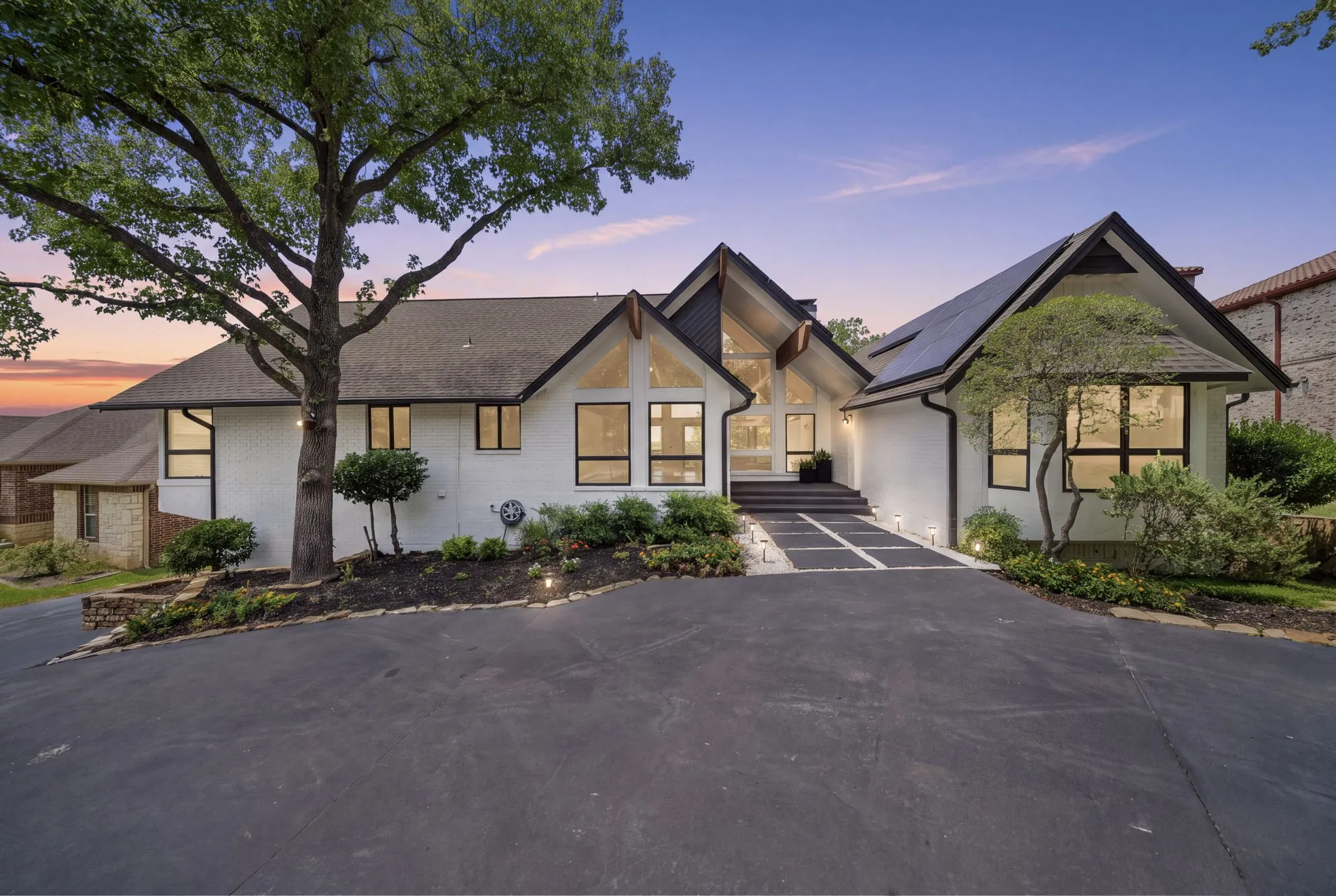 Contemporary white stucco exterior with black trim, a gabled roofline, and large fixed-pane windows