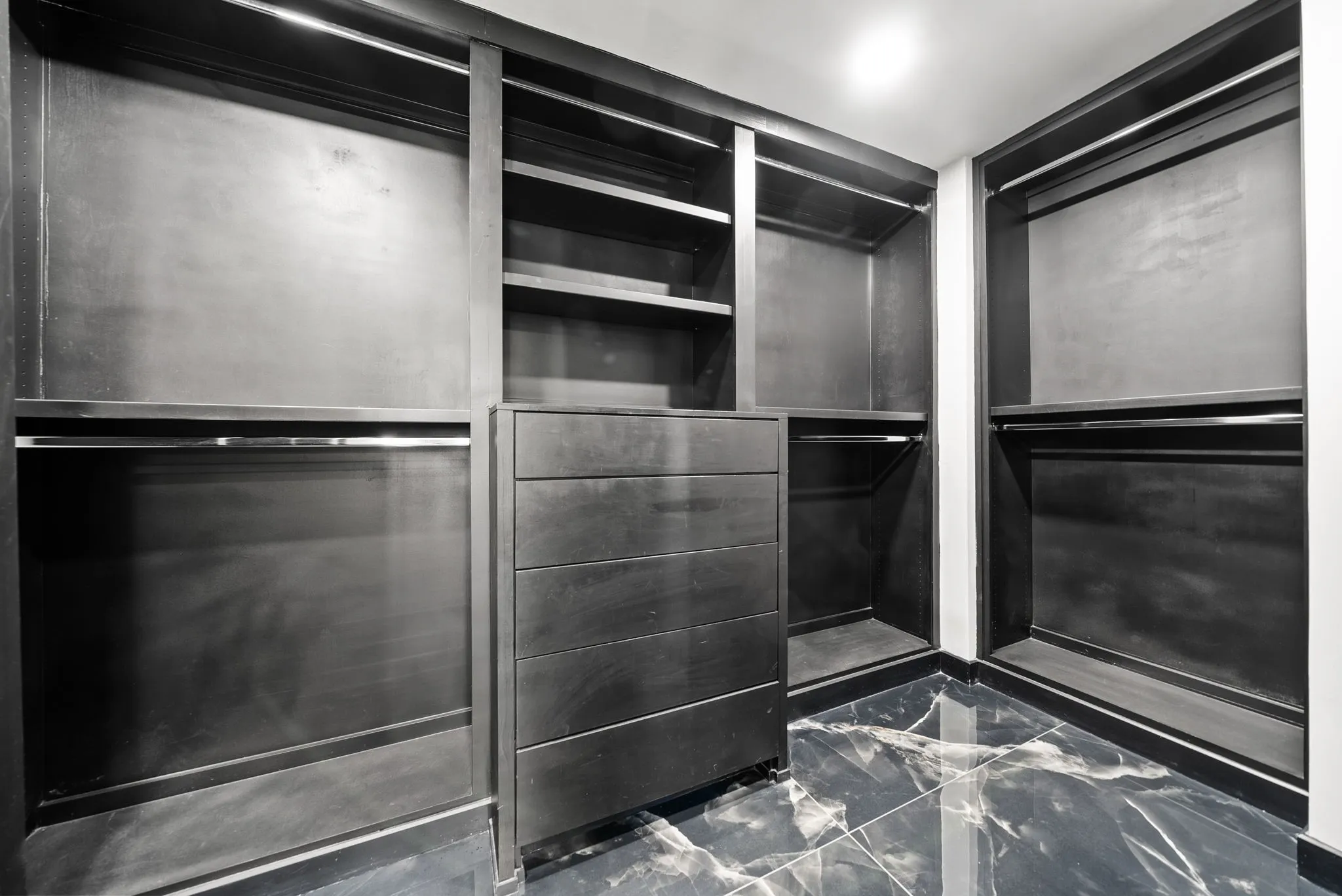 Custom closet system featuring dark wood-finish cabinetry, integrated shelving, and a central drawer unit