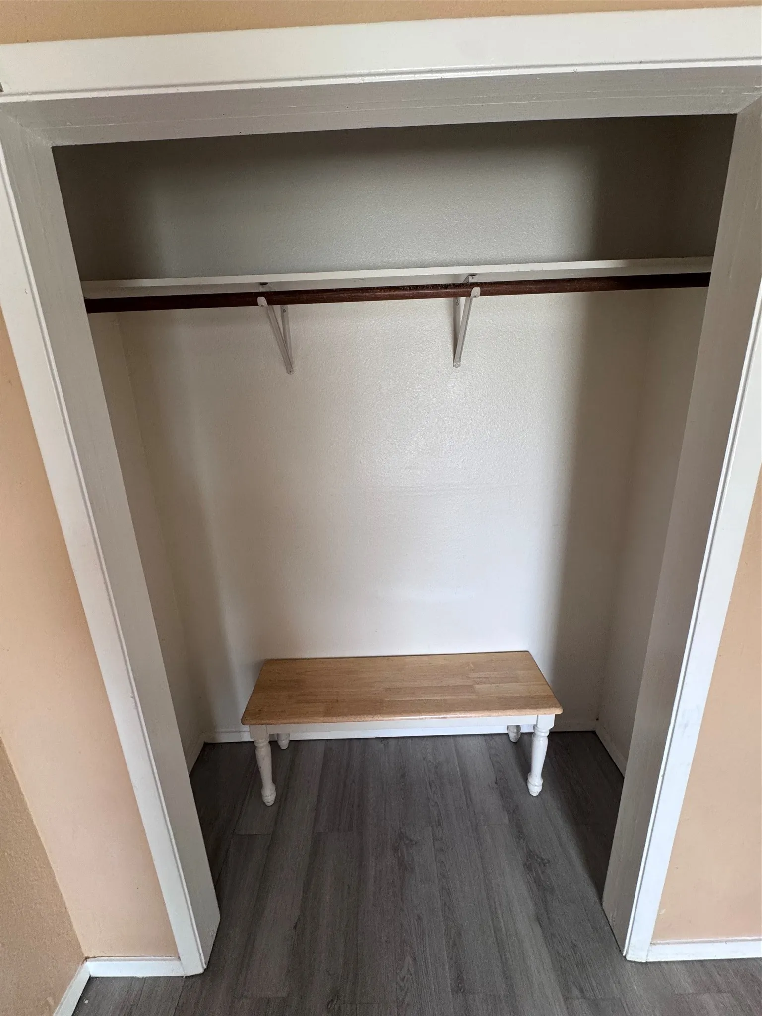 Recessed alcove featuring a wall-mounted rod, white support brackets, and grey wood-finish flooring
