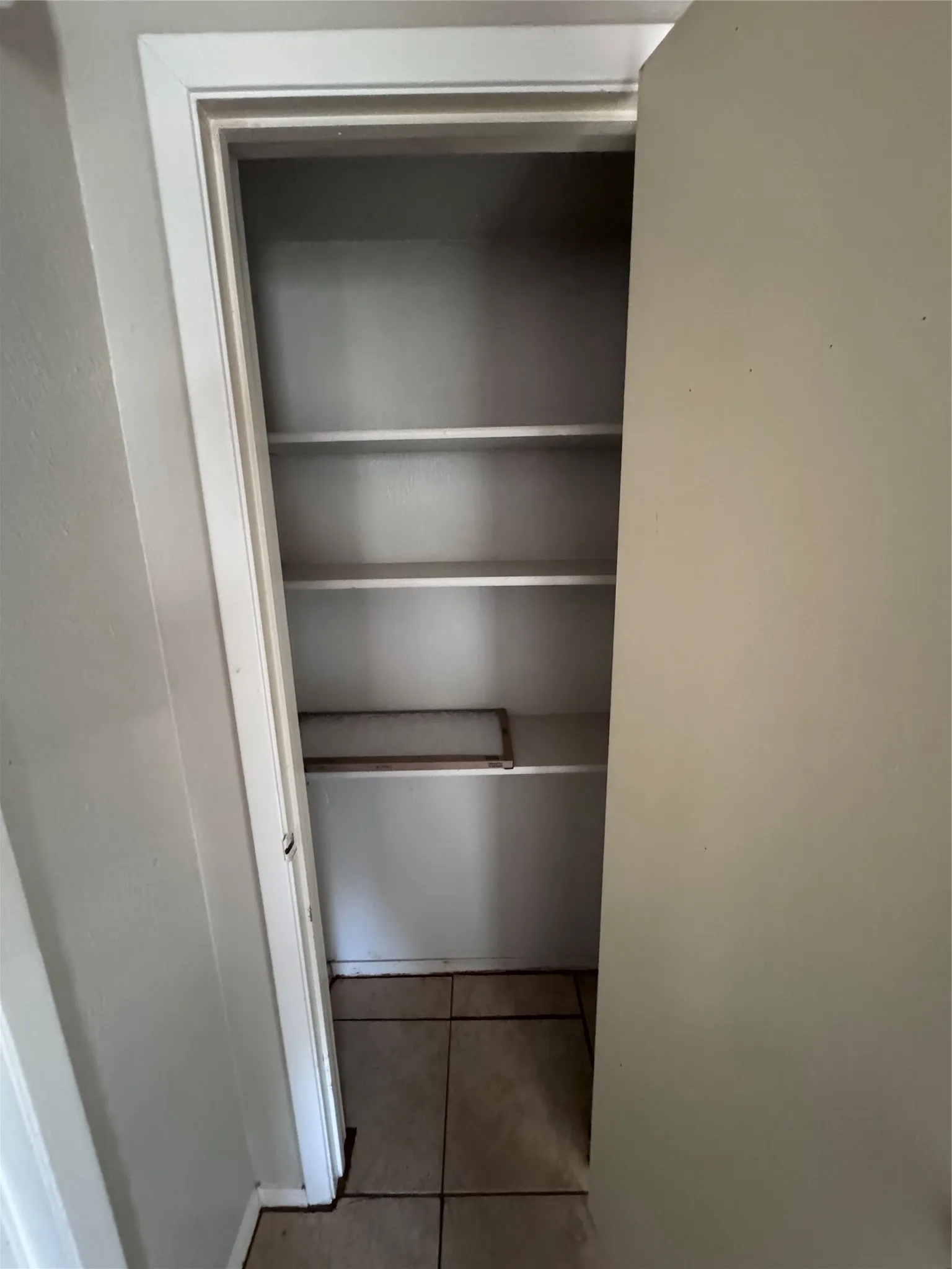 Built-in shelving unit featuring multiple white shelves and tile flooring